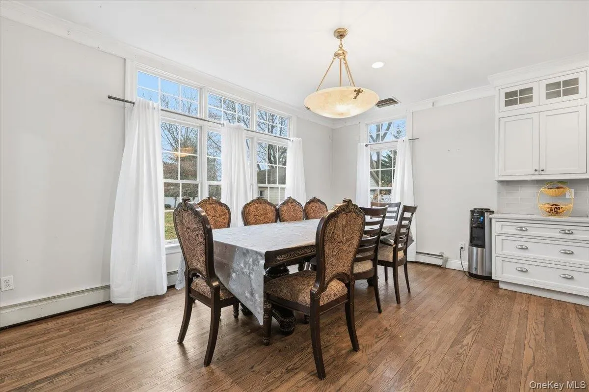 Dining room featuring crown molding, dark wood finished floors, and baseboard heating Dining room featuring crown molding, dark wood finished floors, and baseboard heating