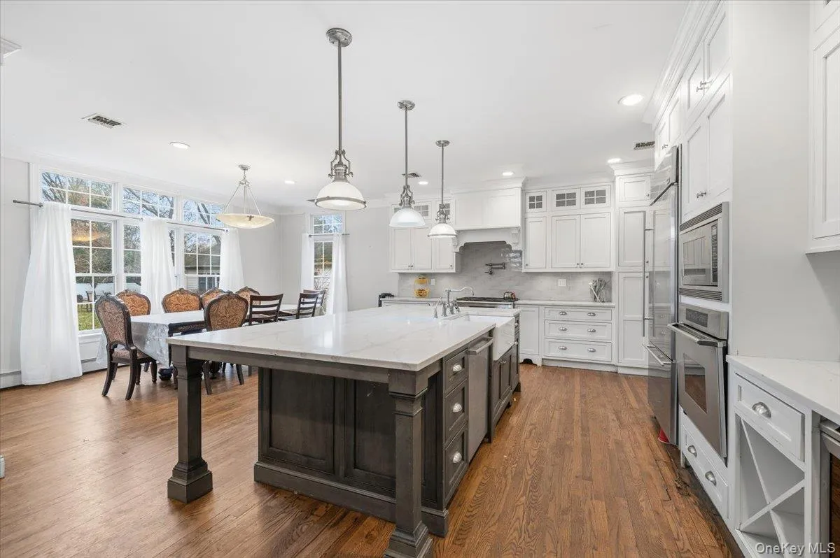 Kitchen with glass insert cabinets, white cabinetry, light stone countertops, built in appliances, and recessed lighting Kitchen with glass insert cabinets, white cabinetry, light stone countertops, built in appliances, and recessed lighting