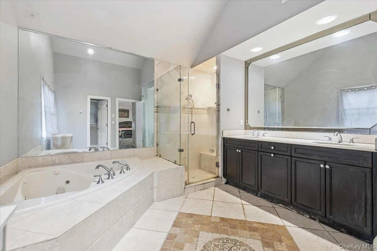 Bathroom with double vanity, vaulted ceiling, a jetted tub, a stall shower, and recessed lighting Bathroom with double vanity, vaulted ceiling, a jetted tub, a stall shower, and recessed lighting