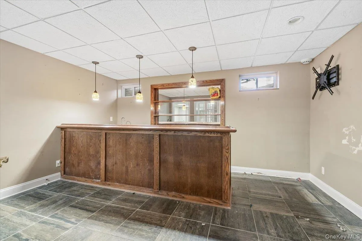 Indoor wet bar featuring a drop ceiling and hanging light fixtures Indoor wet bar featuring a drop ceiling and hanging light fixtures