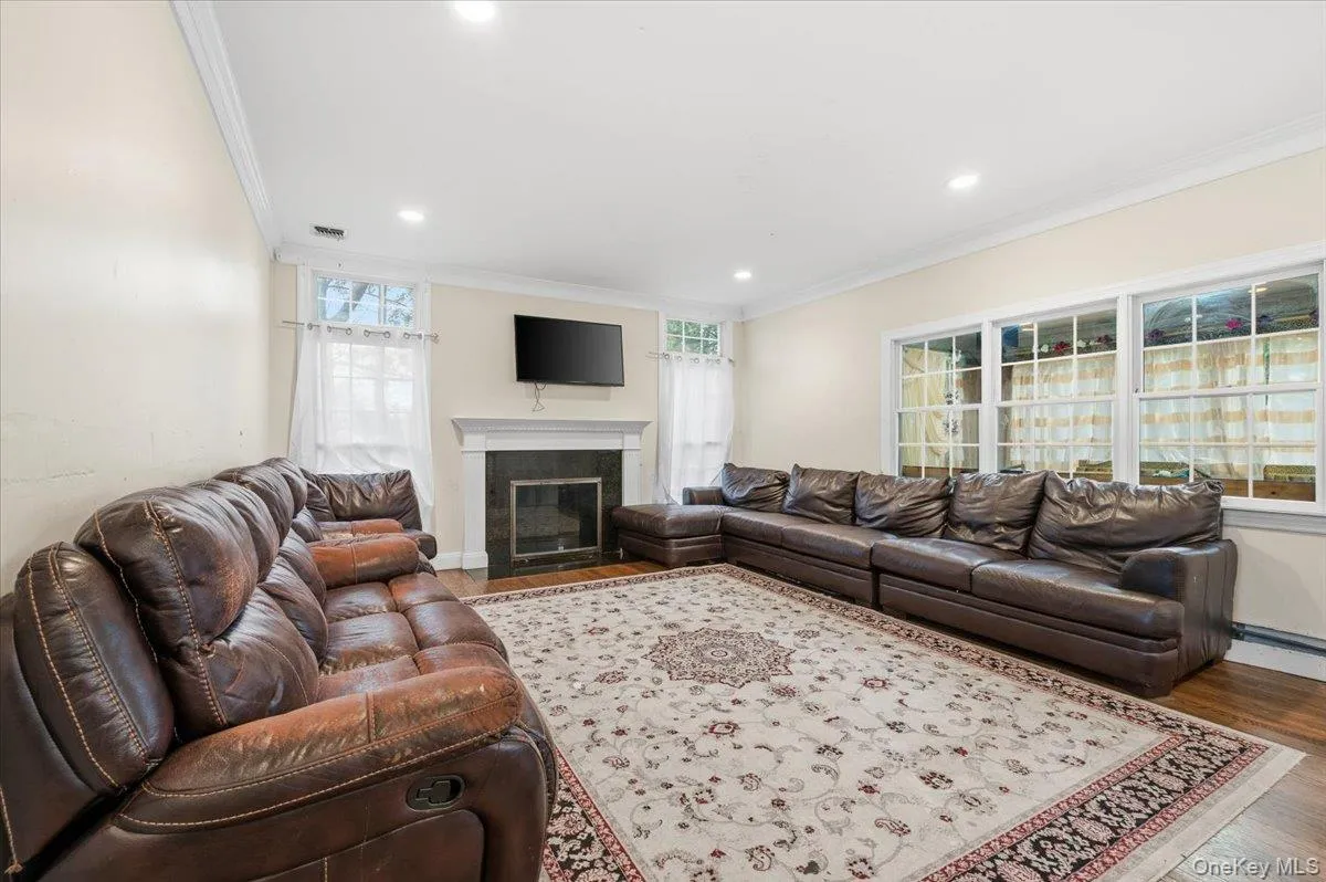 Family room featuring wood finished floors, crown molding, a fireplace with flush hearth, and recessed lighting Family room featuring wood finished floors, crown molding, a fireplace with flush hearth, and recessed lighting