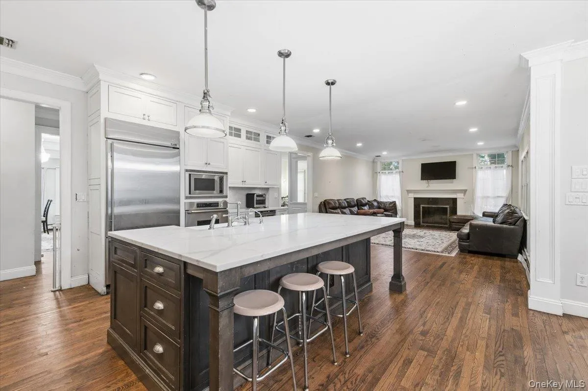 Kitchen with a breakfast bar, white cabinets, dark brown cabinets, crown molding, and a fireplace Kitchen with a breakfast bar, white cabinets, dark brown cabinets, crown molding, and a fireplace