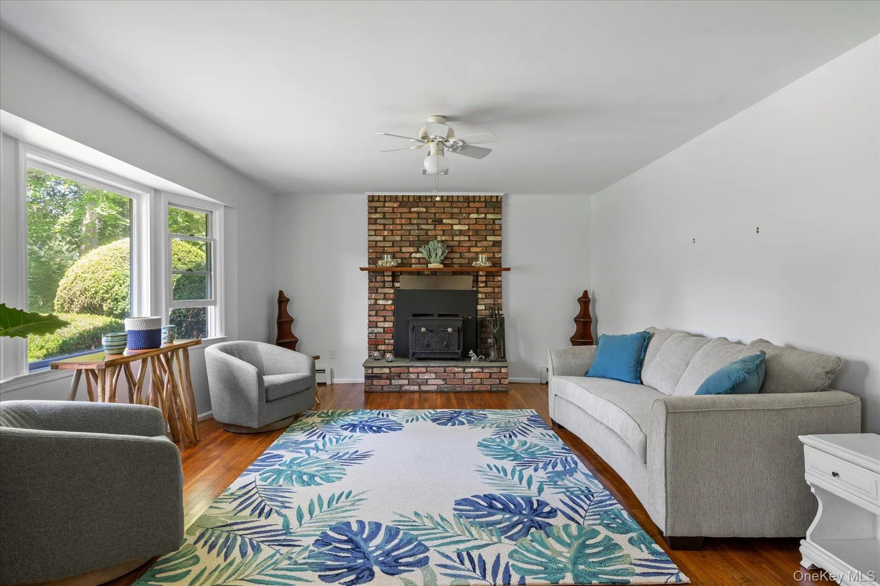 Living area featuring wood finished floors, ceiling fan, and a brick fireplace Living area featuring wood finished floors, ceiling fan, and a brick fireplace