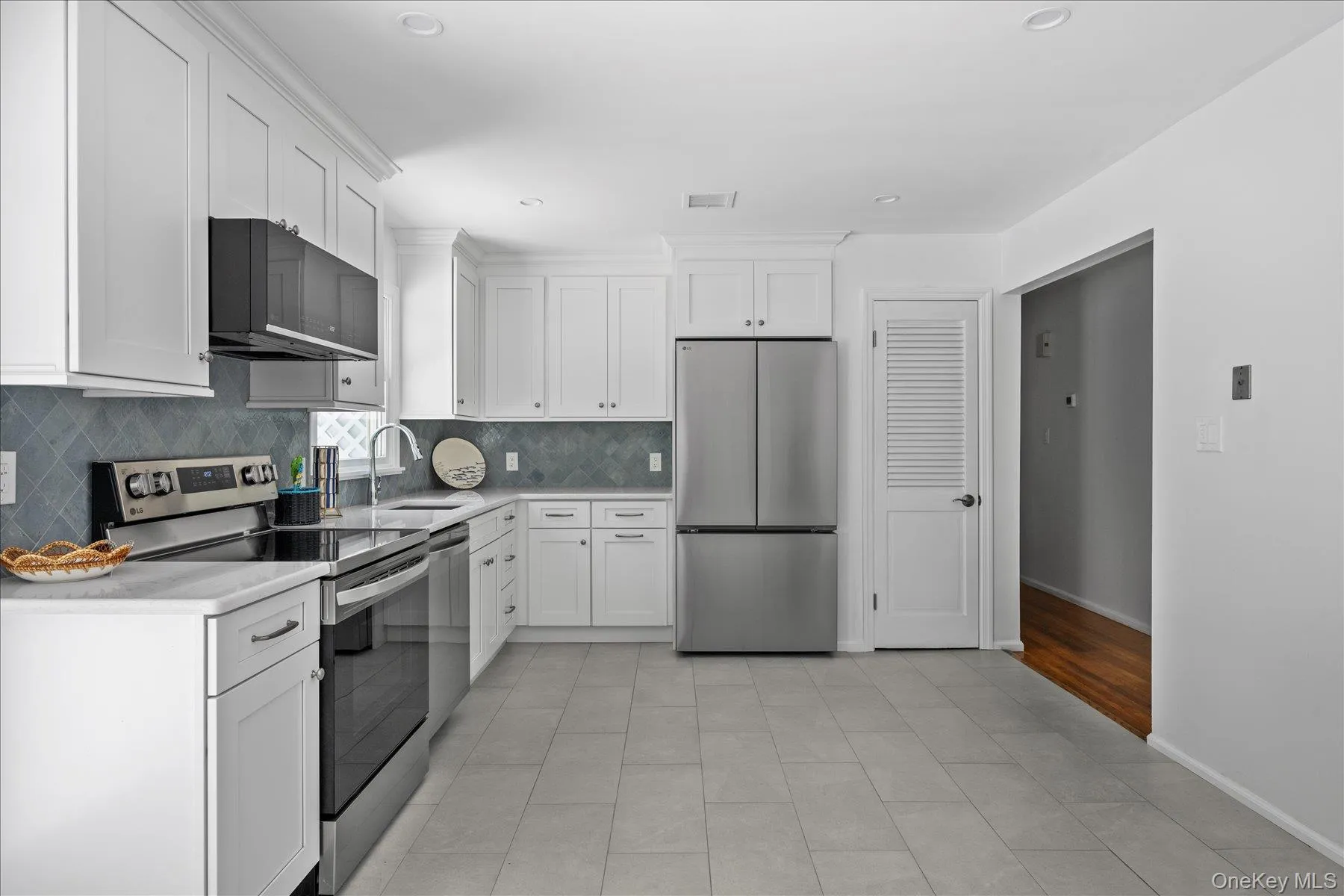 Kitchen featuring appliances with stainless steel finishes, white cabinets, backsplash, light tile patterned flooring, and recessed lighting Kitchen featuring appliances with stainless steel finishes, white cabinets, backsplash, light tile patterned flooring, and recessed lighting