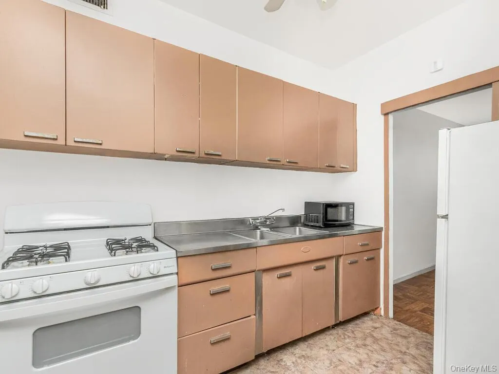 Kitchen with white appliances, stainless steel countertops, and a ceiling fan Kitchen with white appliances, stainless steel countertops, and a ceiling fan