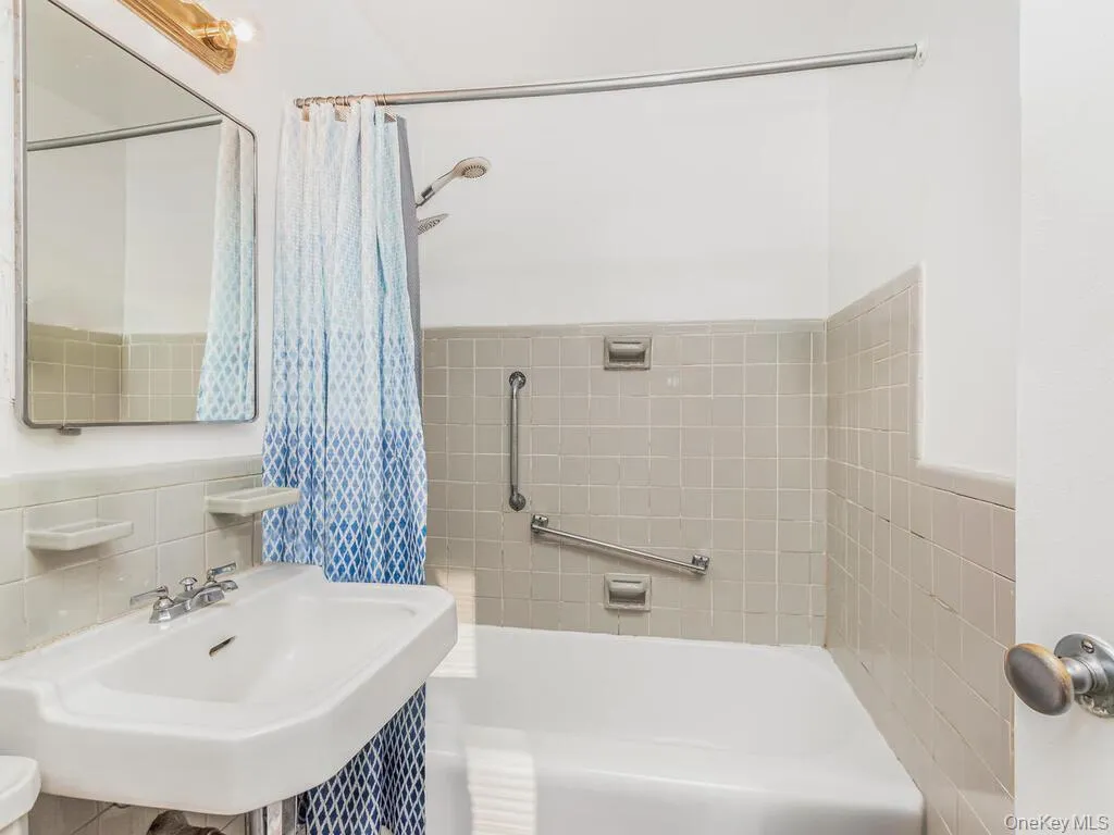 Full bathroom featuring shower / tub combo with curtain and tile walls Full bathroom featuring shower / tub combo with curtain and tile walls