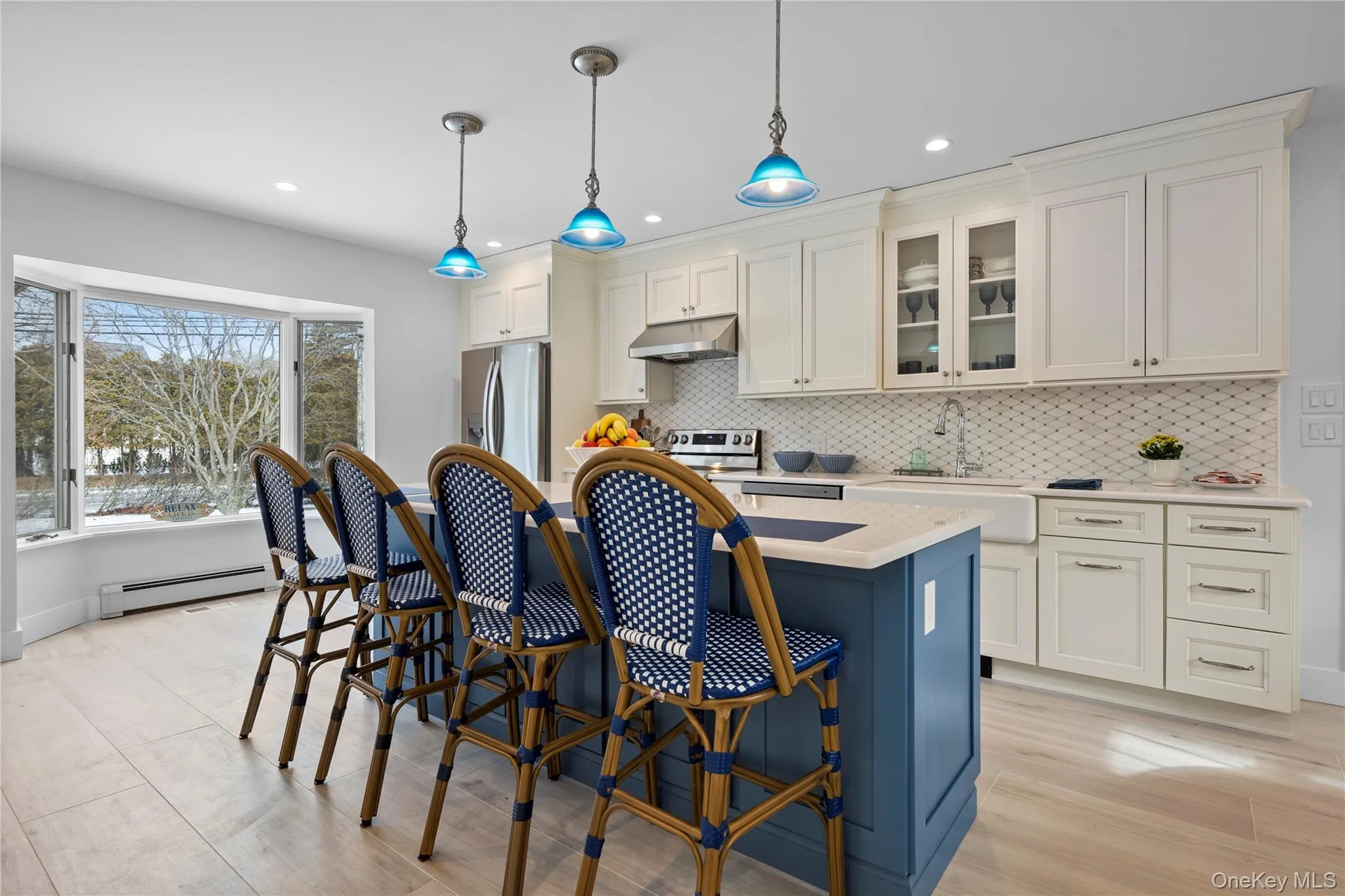 Kitchen featuring glass insert cabinets, blue cabinetry, decorative light fixtures, a breakfast bar area, and stainless steel appliances Kitchen featuring glass insert cabinets, blue cabinetry, decorative light fixtures, a breakfast bar area, and stainless steel appliances