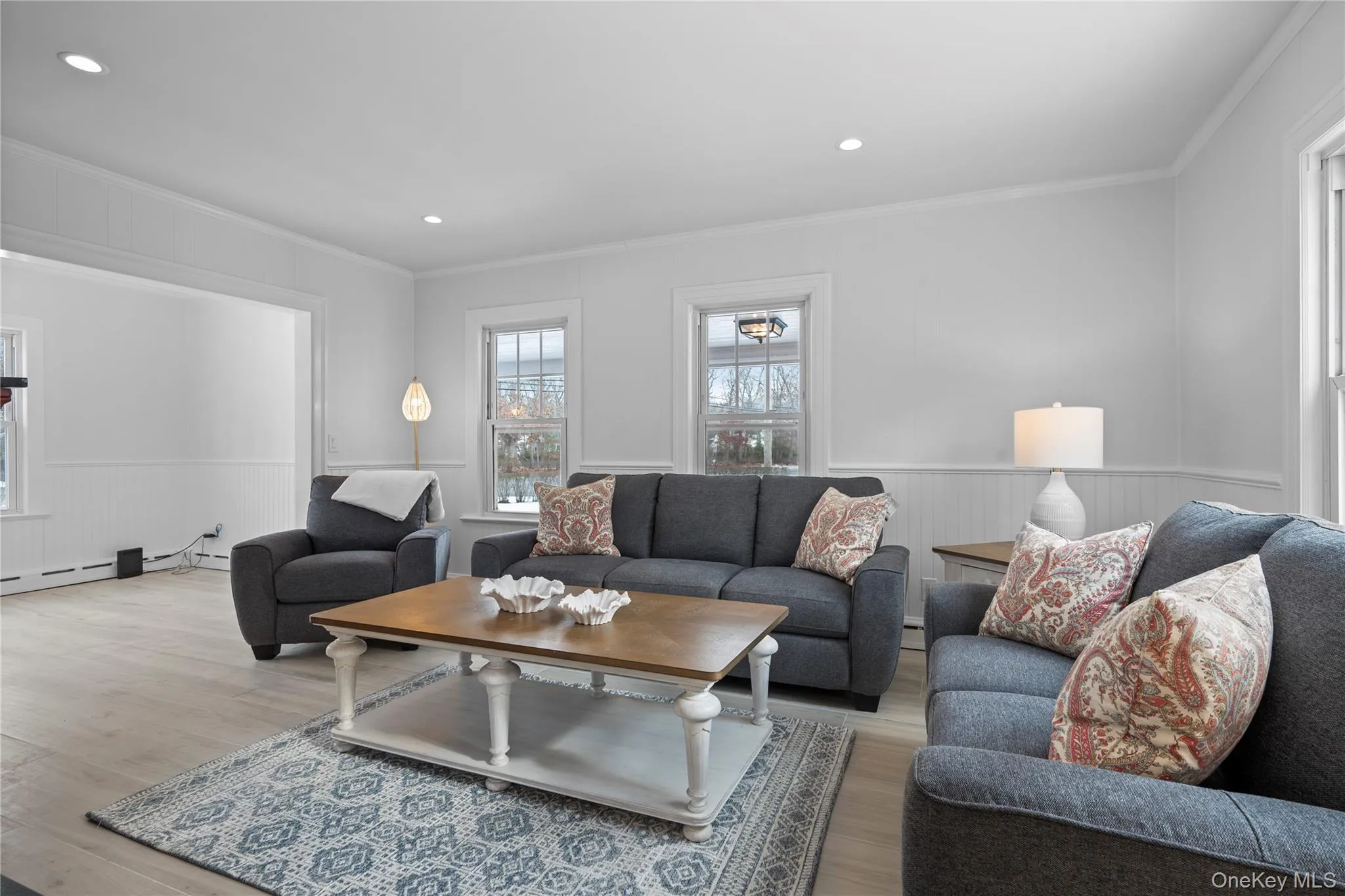 Living area featuring wainscoting, ornamental molding, recessed lighting, and wood finished floors Living area featuring wainscoting, ornamental molding, recessed lighting, and wood finished floors