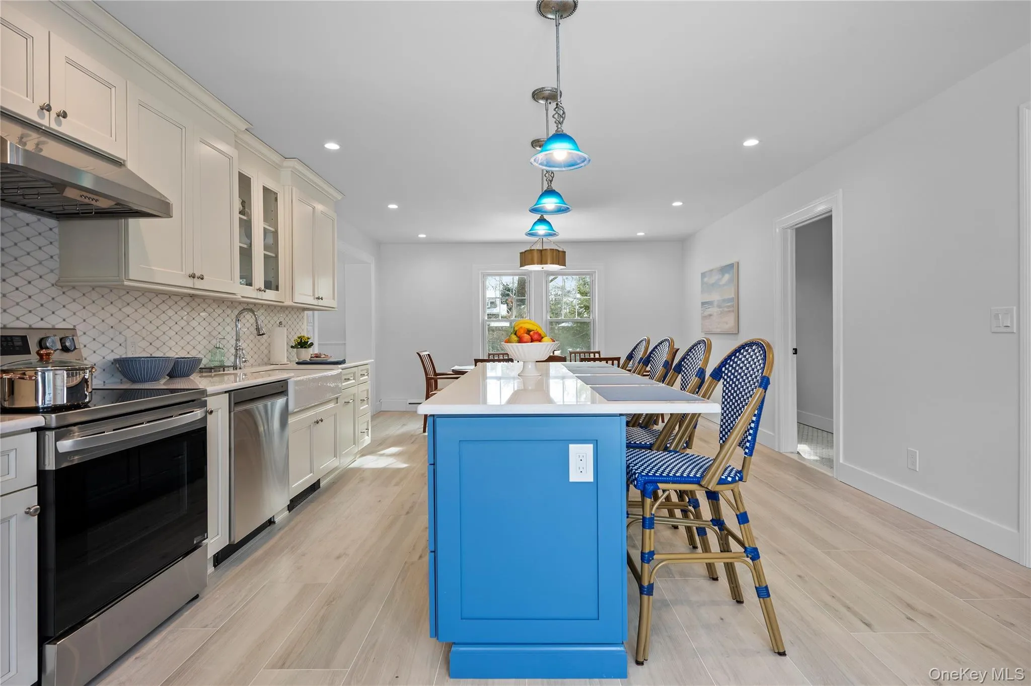 Kitchen featuring stainless steel appliances, hanging light fixtures, blue cabinets, a breakfast bar, and tasteful backsplash Kitchen featuring stainless steel appliances, hanging light fixtures, blue cabinets, a breakfast bar, and tasteful backsplash