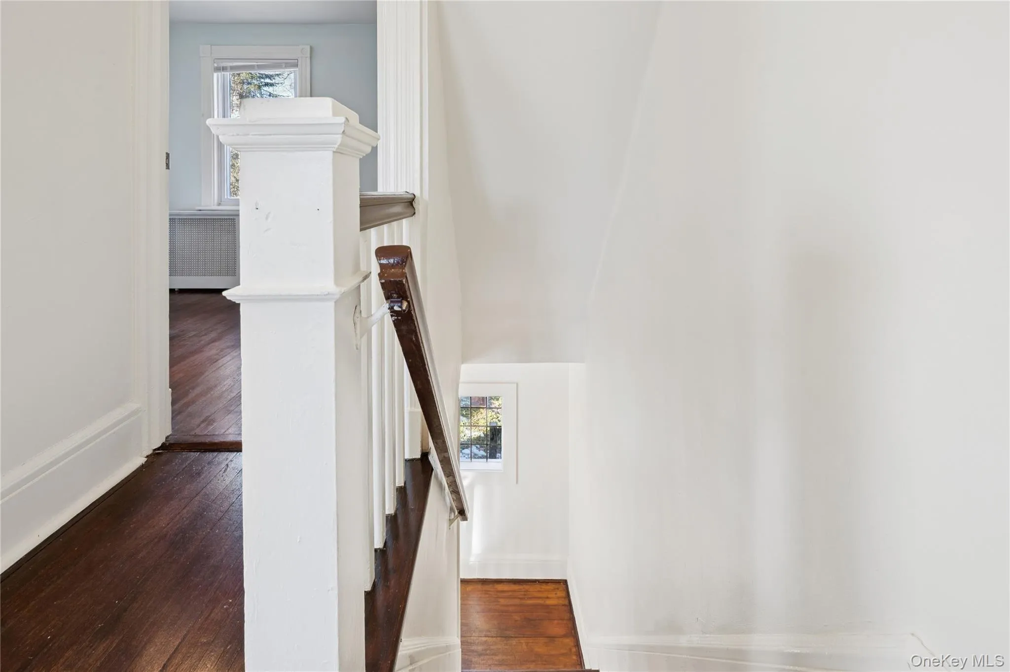 Stairs featuring healthy amount of natural light, wood-type flooring, and radiator heating unit Stairs featuring healthy amount of natural light, wood-type flooring, and radiator heating unit