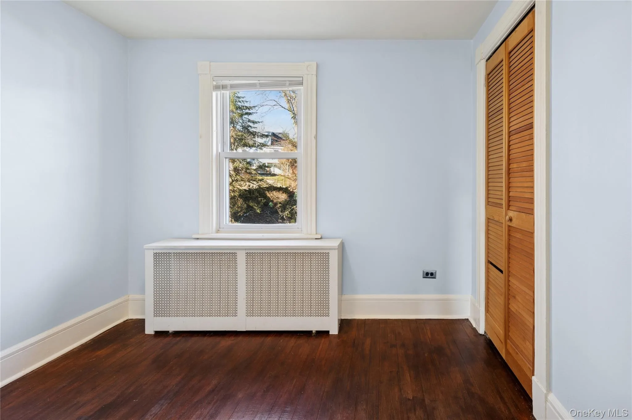 Unfurnished bedroom featuring radiator, dark wood-style floors, and a closet Unfurnished bedroom featuring radiator, dark wood-style floors, and a closet