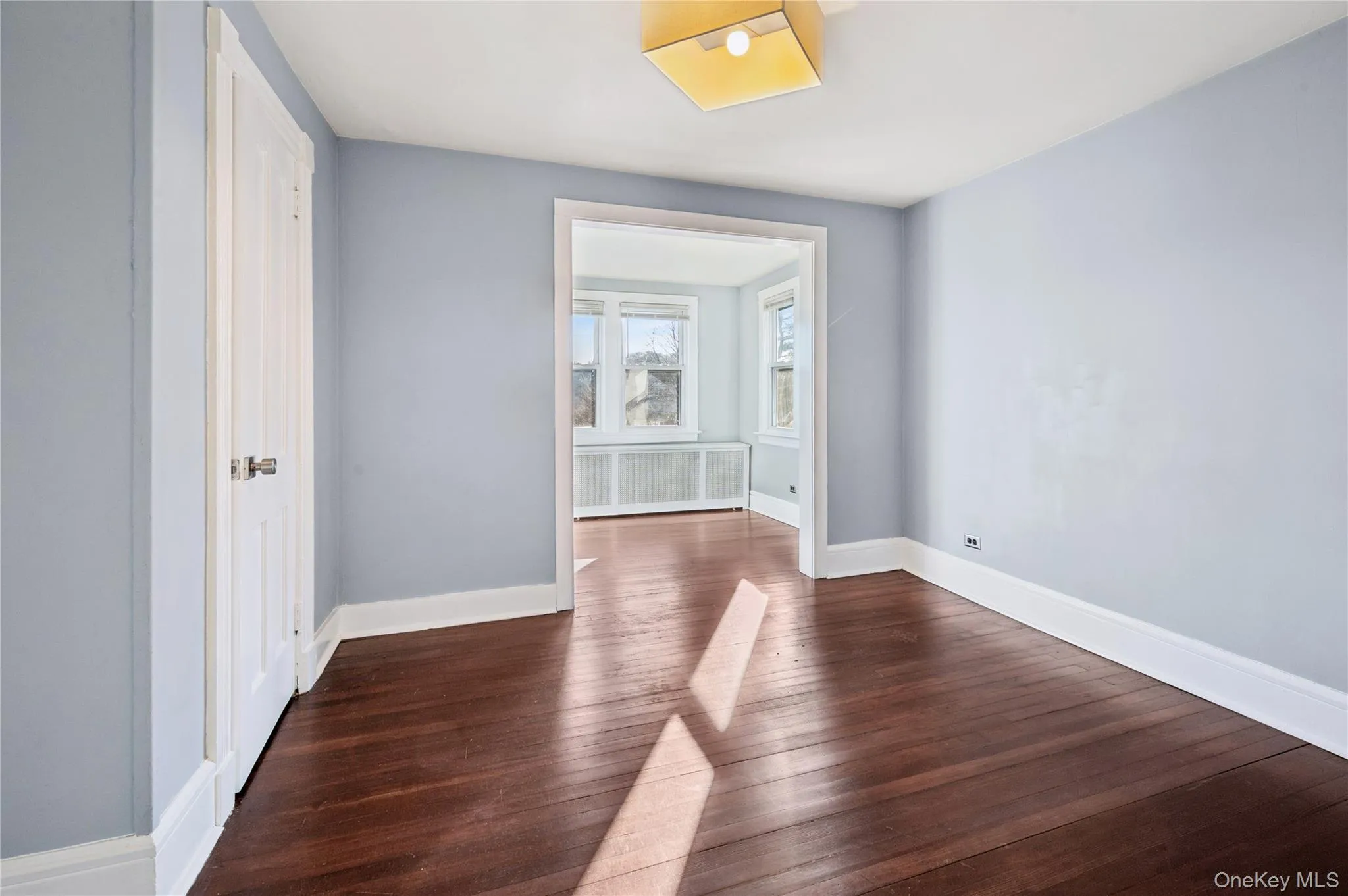 Spare room with radiator and dark wood-style floors Spare room with radiator and dark wood-style floors