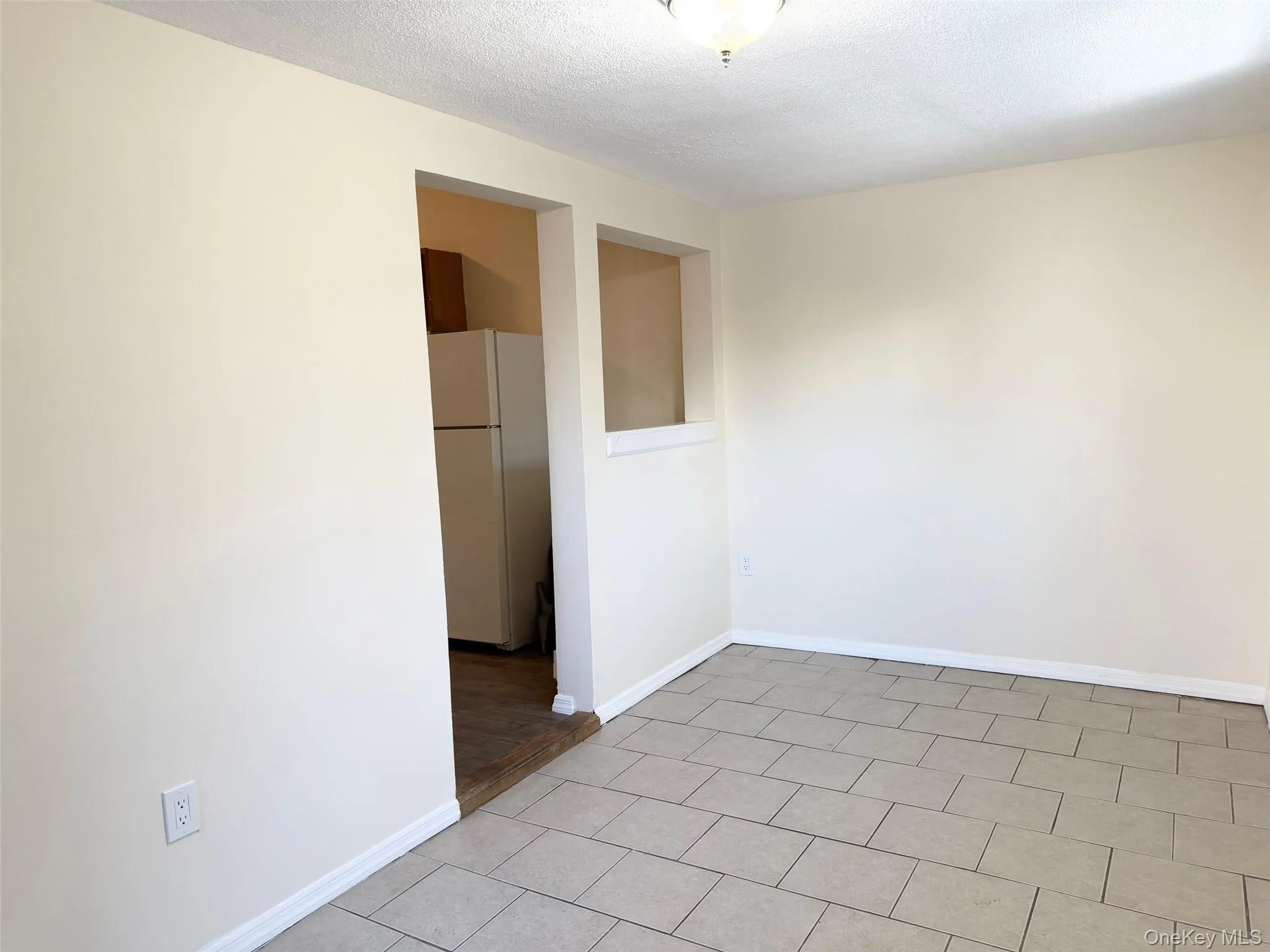 Spare room featuring a textured ceiling and light tile patterned flooring Spare room featuring a textured ceiling and light tile patterned flooring