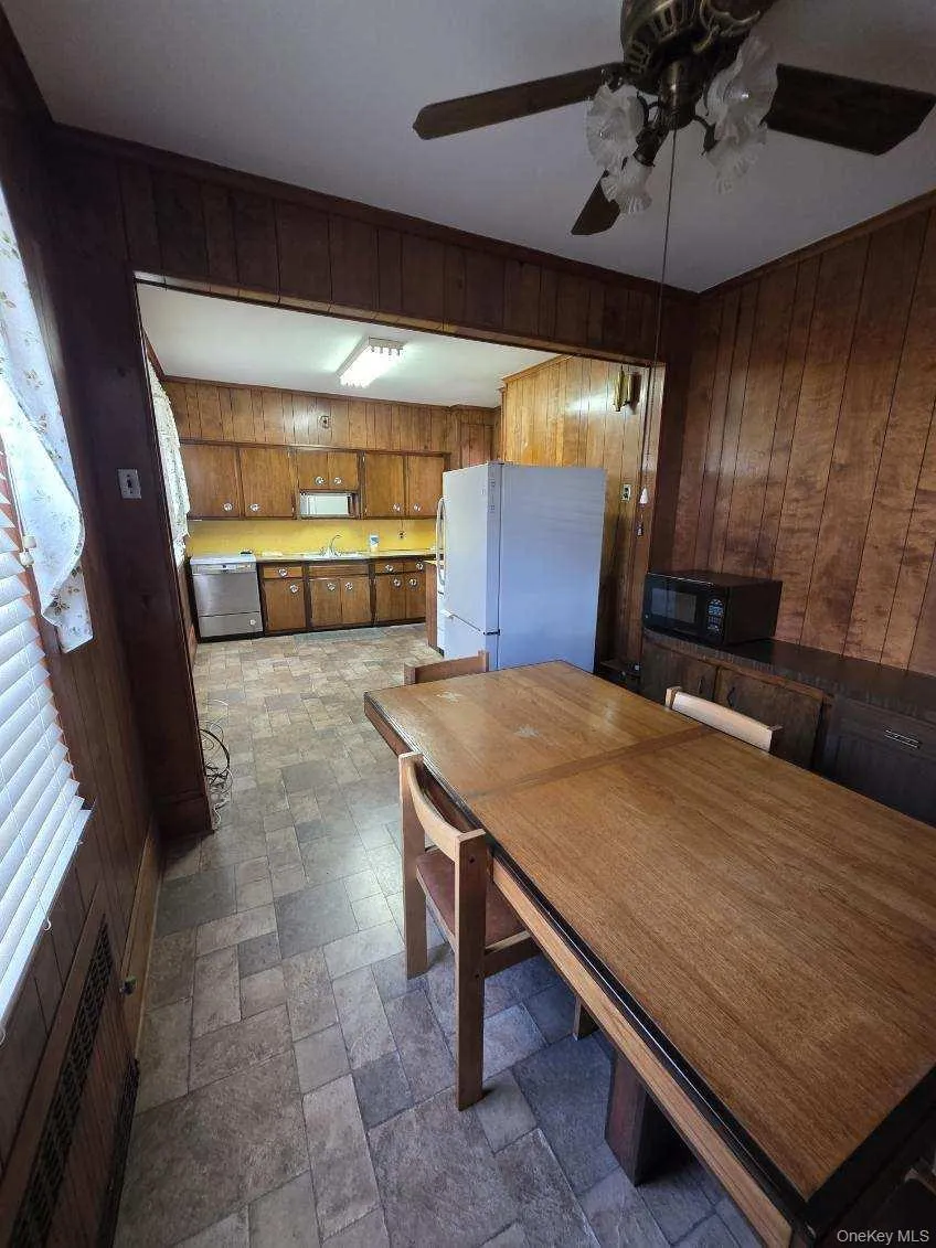 Dining area featuring wood walls, stone finish floors, and ceiling fan Dining area featuring wood walls, stone finish floors, and ceiling fan