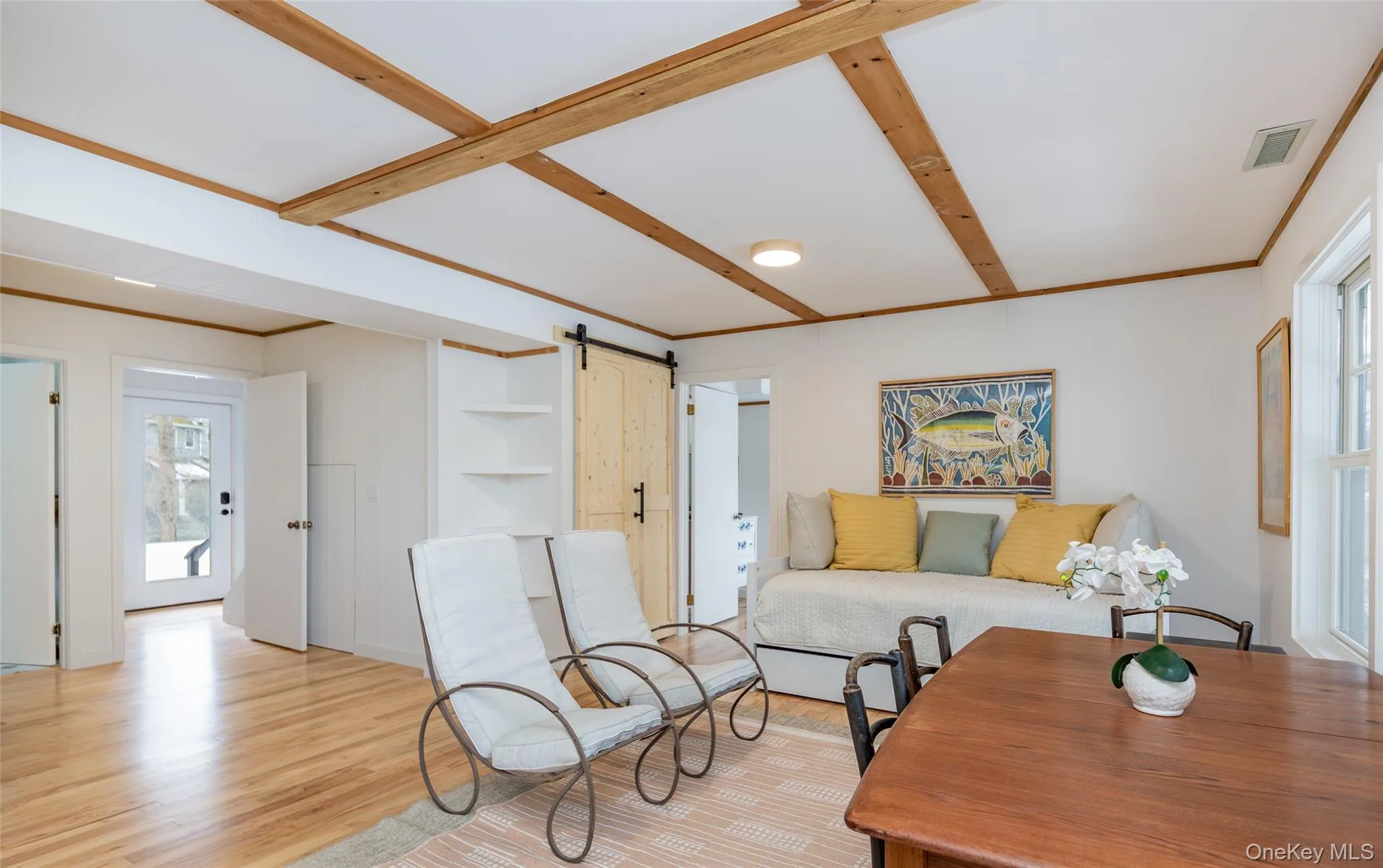 Living room with a barn door, light wood-style flooring, and ornamental molding Living room with a barn door, light wood-style flooring, and ornamental molding