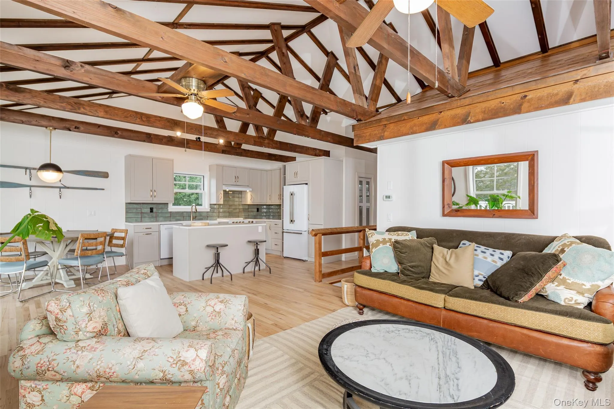 Living room with a ceiling fan, light wood-style floors, beamed ceiling, and high vaulted ceiling Living room with a ceiling fan, light wood-style floors, beamed ceiling, and high vaulted ceiling