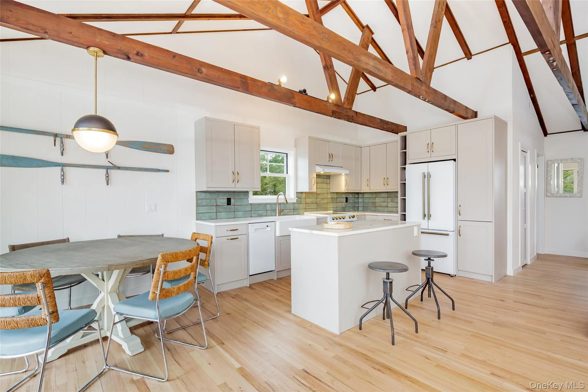 Kitchen featuring a breakfast bar, white appliances, light countertops, white cabinetry, and high vaulted ceiling Kitchen featuring a breakfast bar, white appliances, light countertops, white cabinetry, and high vaulted ceiling