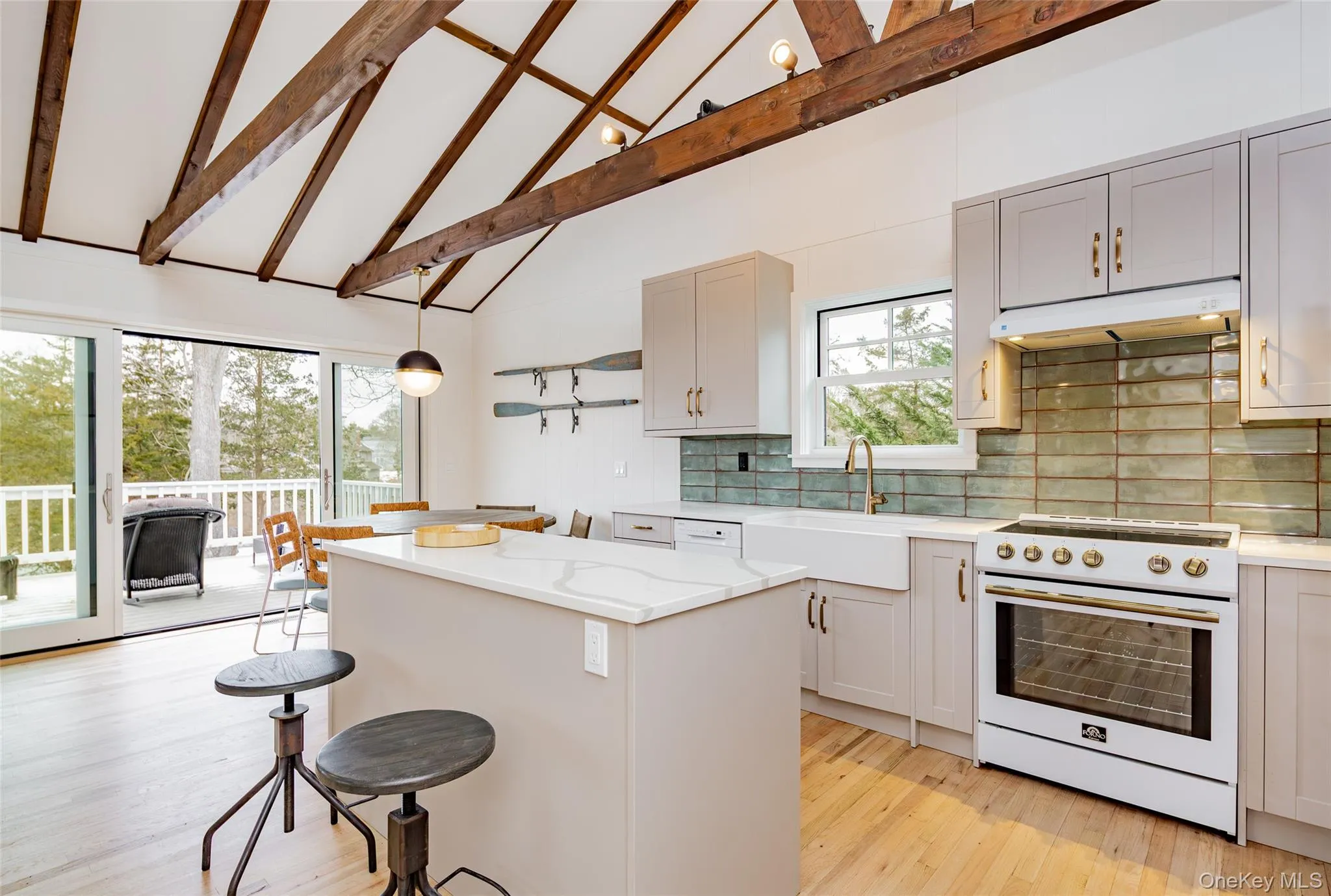 Kitchen with high vaulted ceiling, high end white range, a breakfast bar area, tasteful backsplash, and a kitchen island Kitchen with high vaulted ceiling, high end white range, a breakfast bar area, tasteful backsplash, and a kitchen island