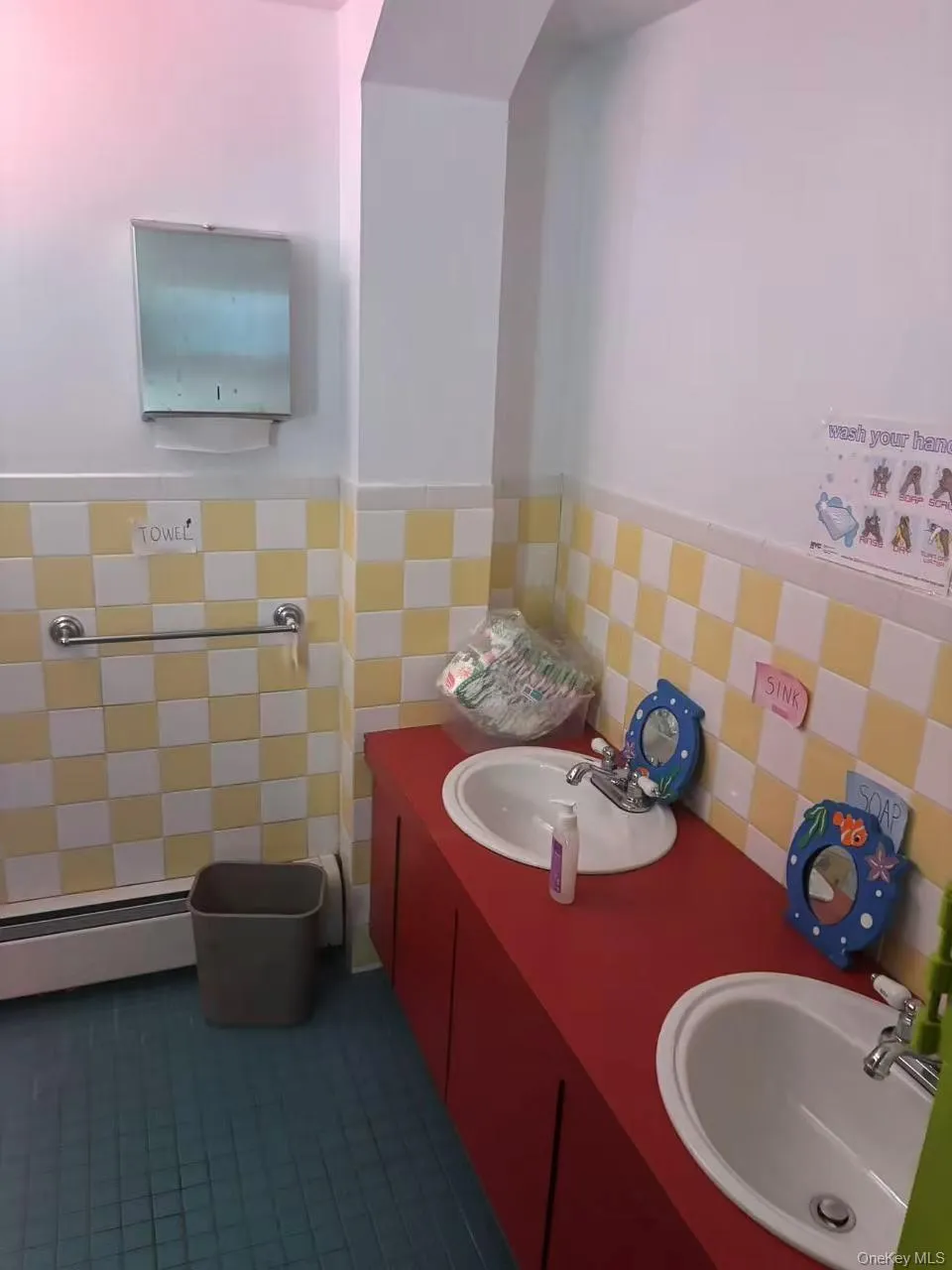 Half bathroom featuring double vanity, tile walls, wainscoting, and baseboard heating Half bathroom featuring double vanity, tile walls, wainscoting, and baseboard heating