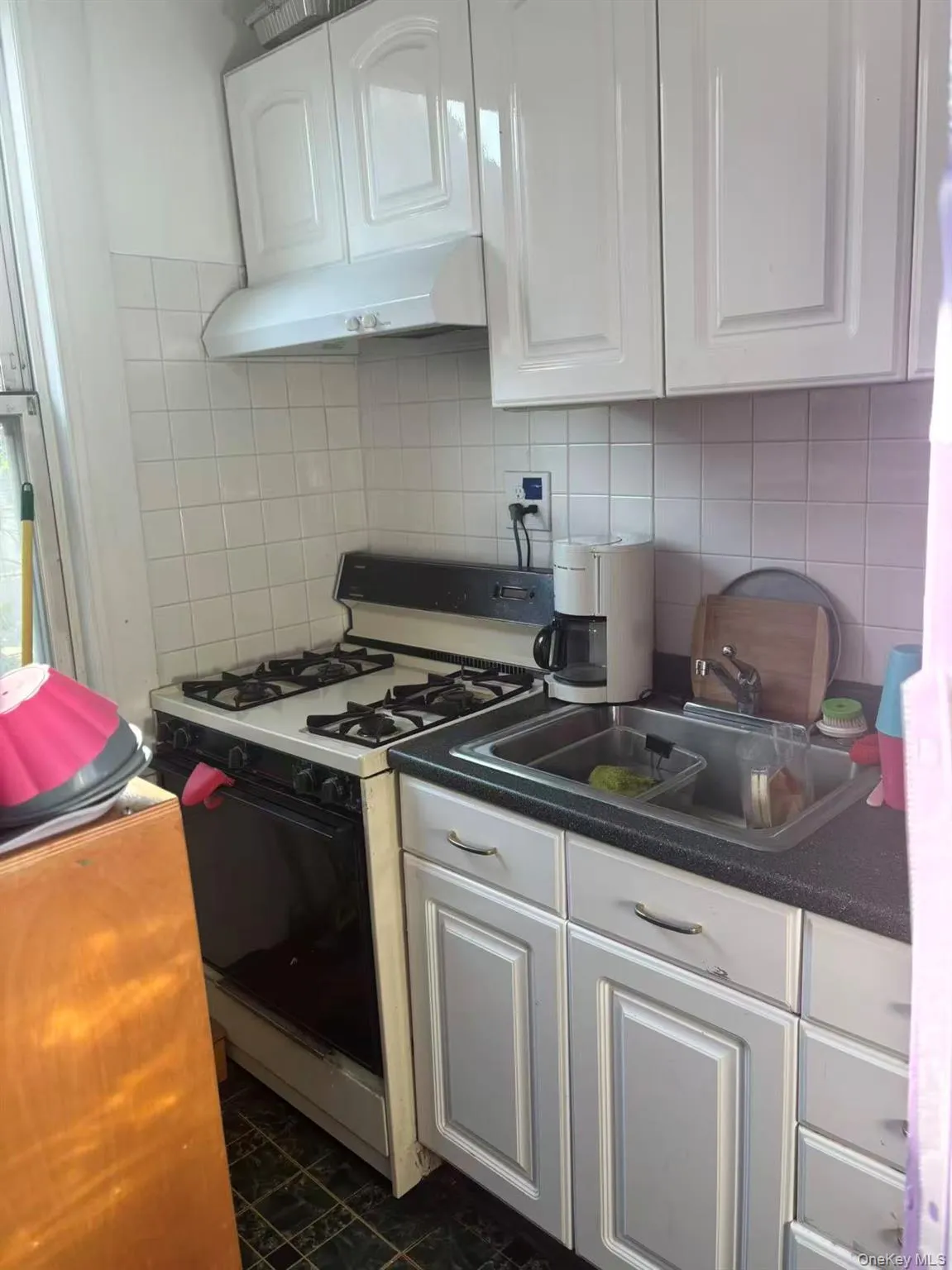 Kitchen with white cabinets, white gas stove, under cabinet range hood, and decorative backsplash Kitchen with white cabinets, white gas stove, under cabinet range hood, and decorative backsplash
