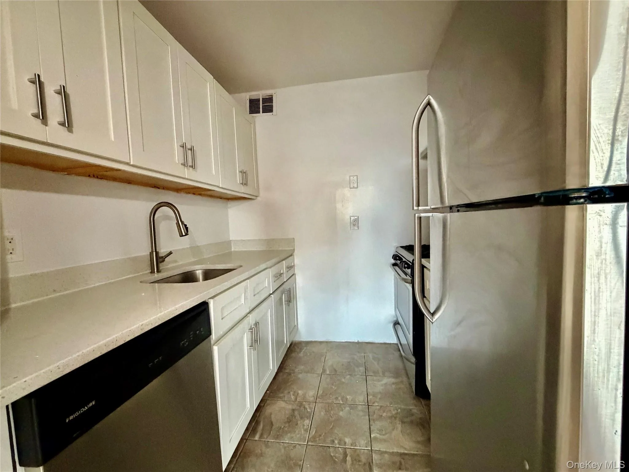 Kitchen featuring stainless steel appliances, white cabinets, and light stone countertops Kitchen featuring stainless steel appliances, white cabinets, and light stone countertops