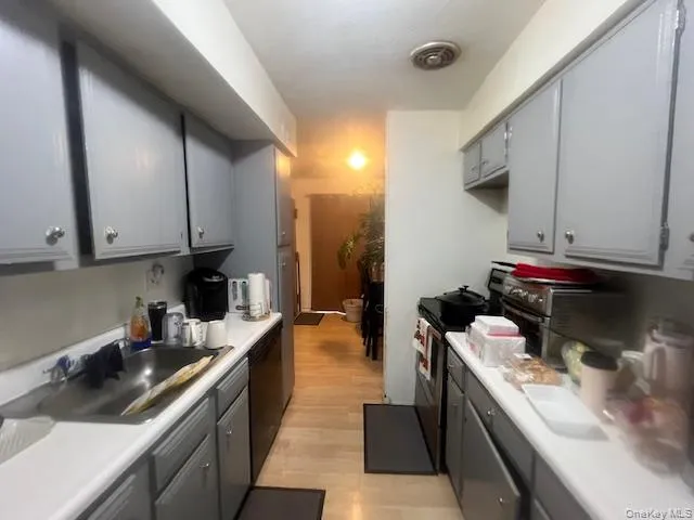 Kitchen featuring gray cabinetry, electric stove, light countertops, dishwasher, and light wood-style flooring Kitchen featuring gray cabinetry, electric stove, light countertops, dishwasher, and light wood-style flooring