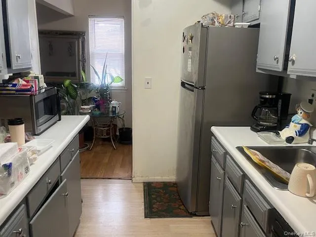 Kitchen featuring gray cabinets, light wood-style flooring, light countertops, and stainless steel appliances Kitchen featuring gray cabinets, light wood-style flooring, light countertops, and stainless steel appliances