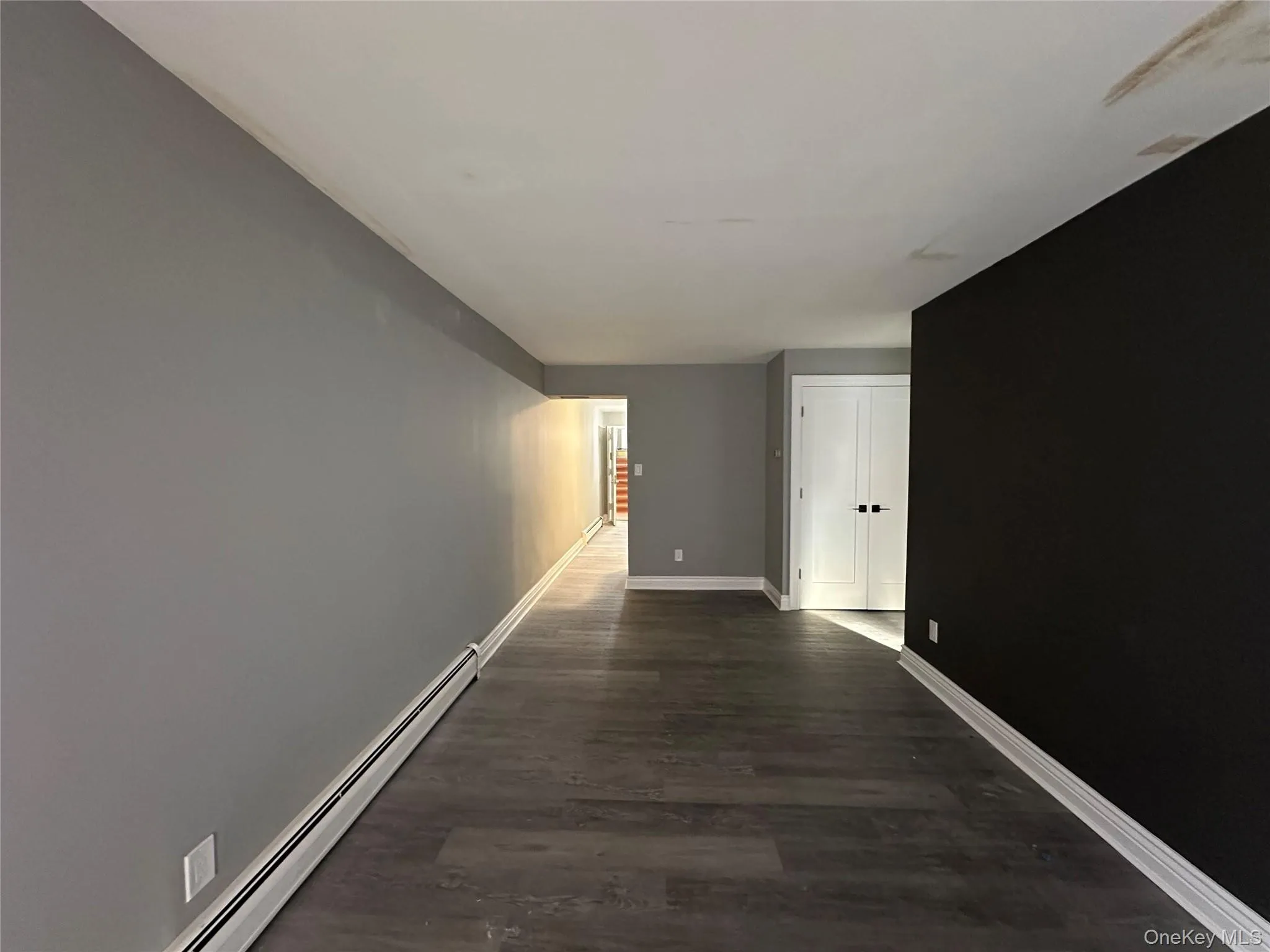Hallway featuring baseboard heating and dark wood-style flooring Hallway featuring baseboard heating and dark wood-style flooring