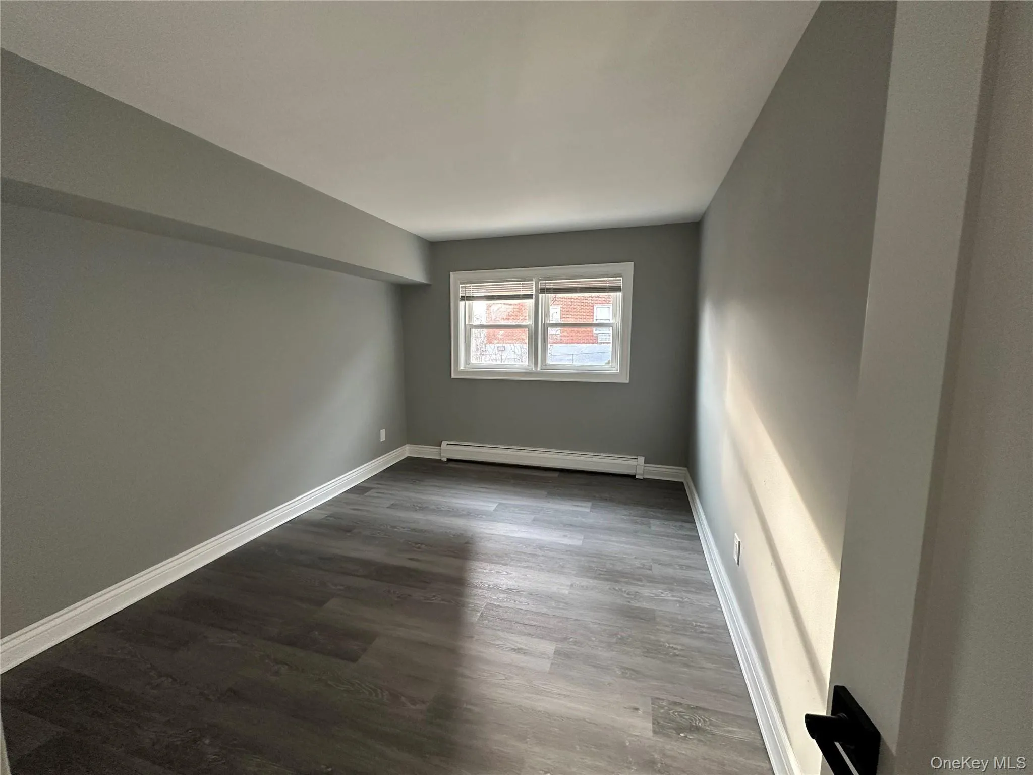 Empty room with wood finished floors and a baseboard radiator Empty room with wood finished floors and a baseboard radiator
