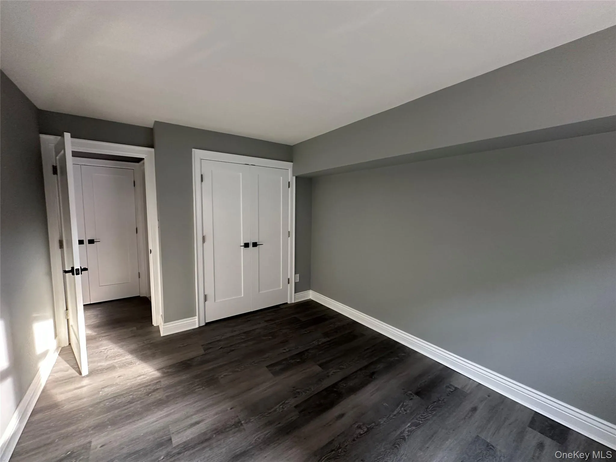 Unfurnished bedroom with a closet and dark wood-type flooring Unfurnished bedroom with a closet and dark wood-type flooring