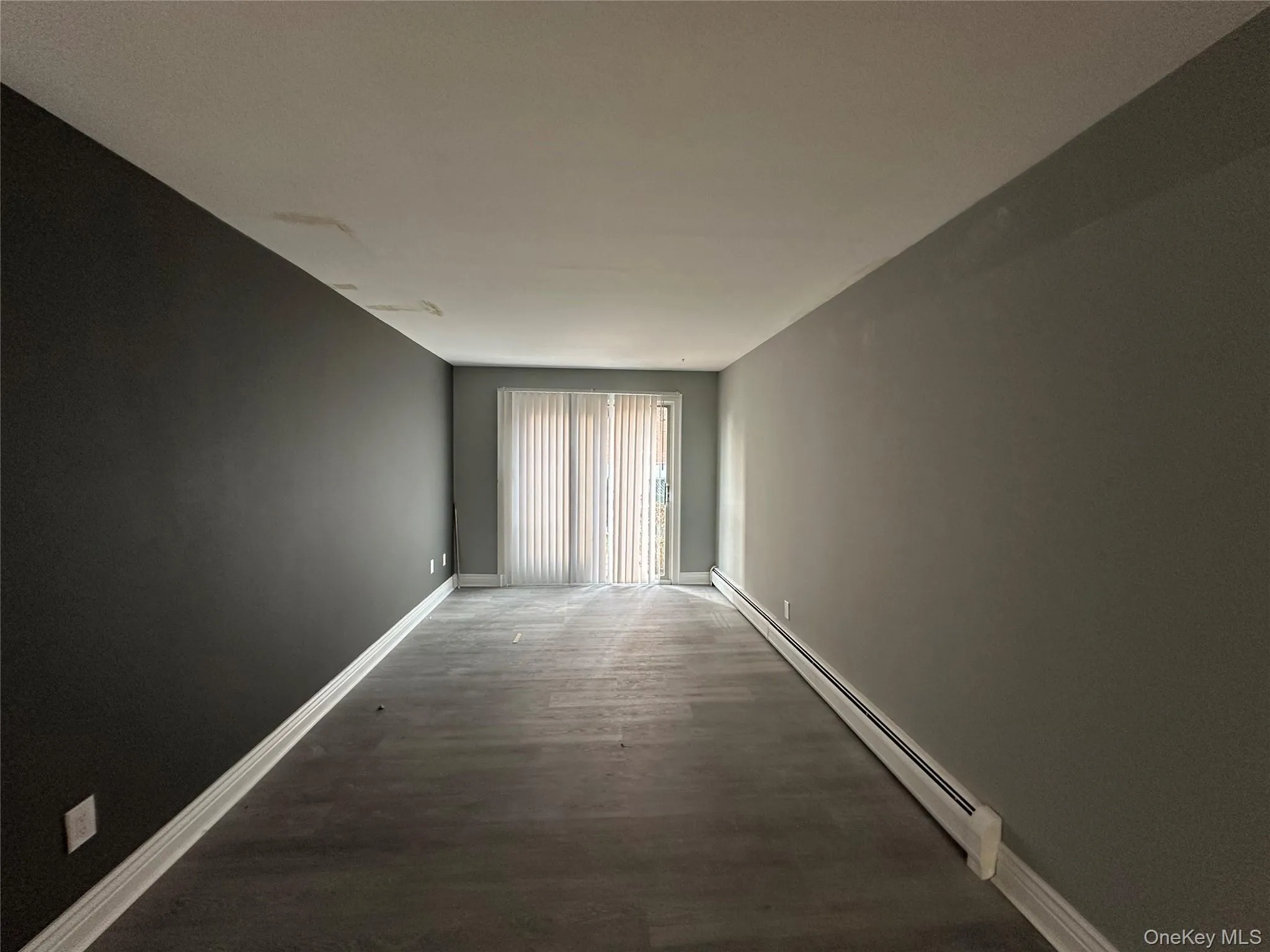 Unfurnished room with a baseboard heating unit and wood finished floors Unfurnished room with a baseboard heating unit and wood finished floors