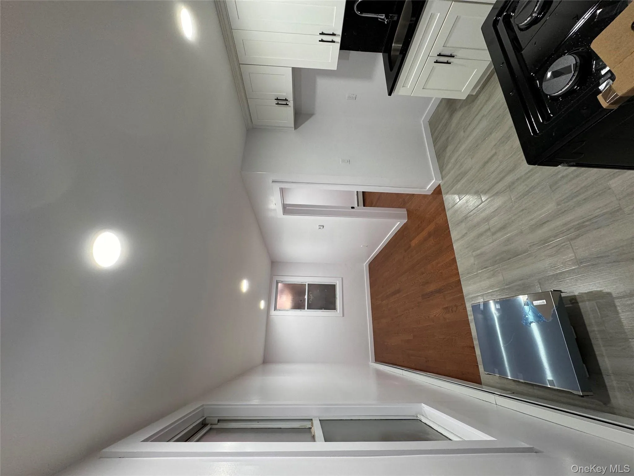 Kitchen with stove, dark countertops, white cabinetry, dark wood finished floors, and recessed lighting Kitchen with stove, dark countertops, white cabinetry, dark wood finished floors, and recessed lighting
