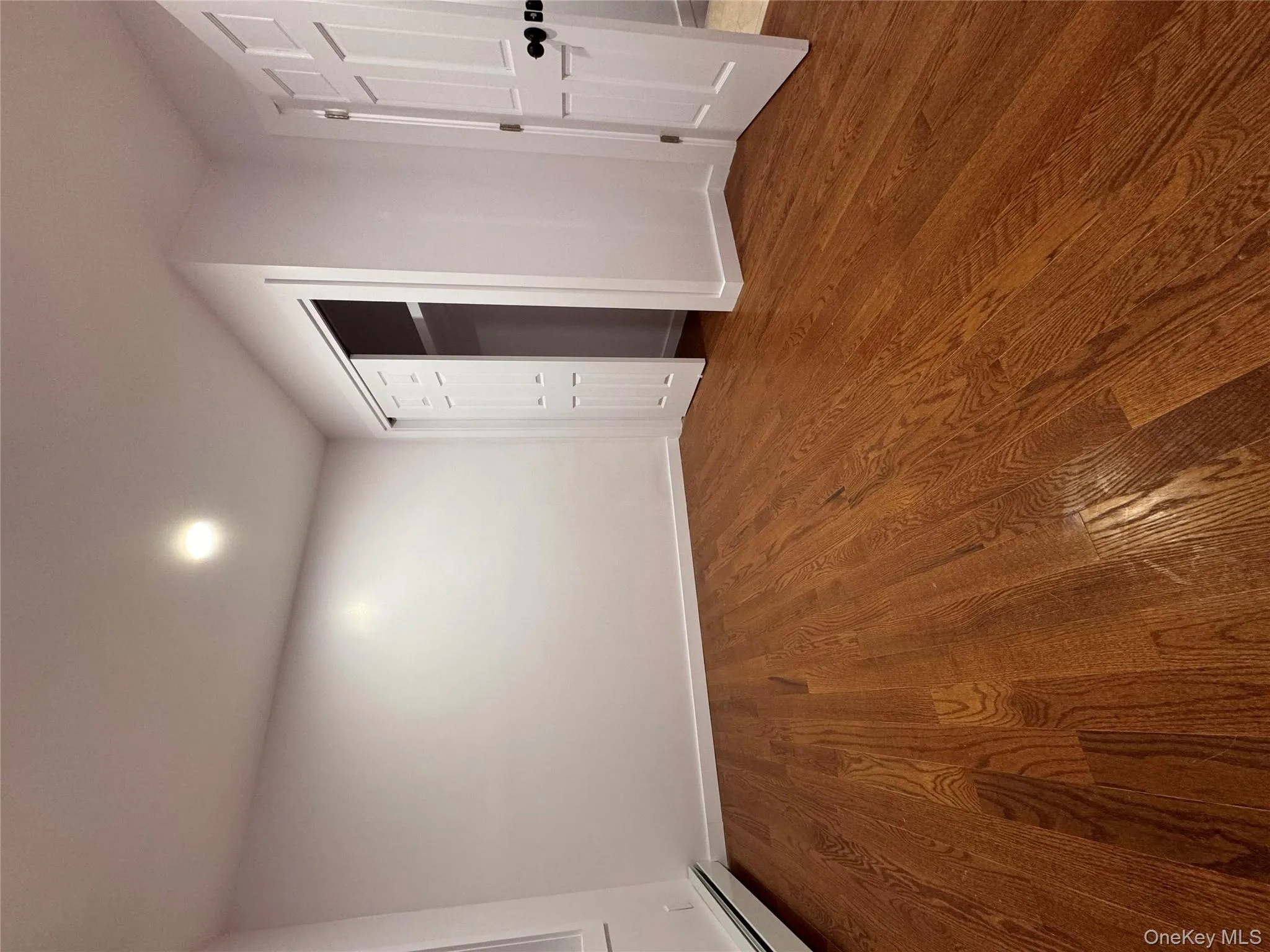 Unfurnished bedroom with dark wood-style flooring, a baseboard radiator, a closet, and recessed lighting Unfurnished bedroom with dark wood-style flooring, a baseboard radiator, a closet, and recessed lighting