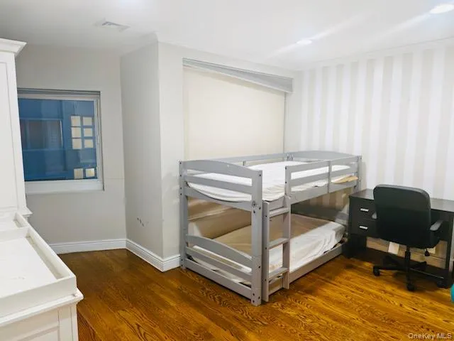 Bedroom featuring dark wood-style floors, wallpapered walls, and ornamental molding Bedroom featuring dark wood-style floors, wallpapered walls, and ornamental molding