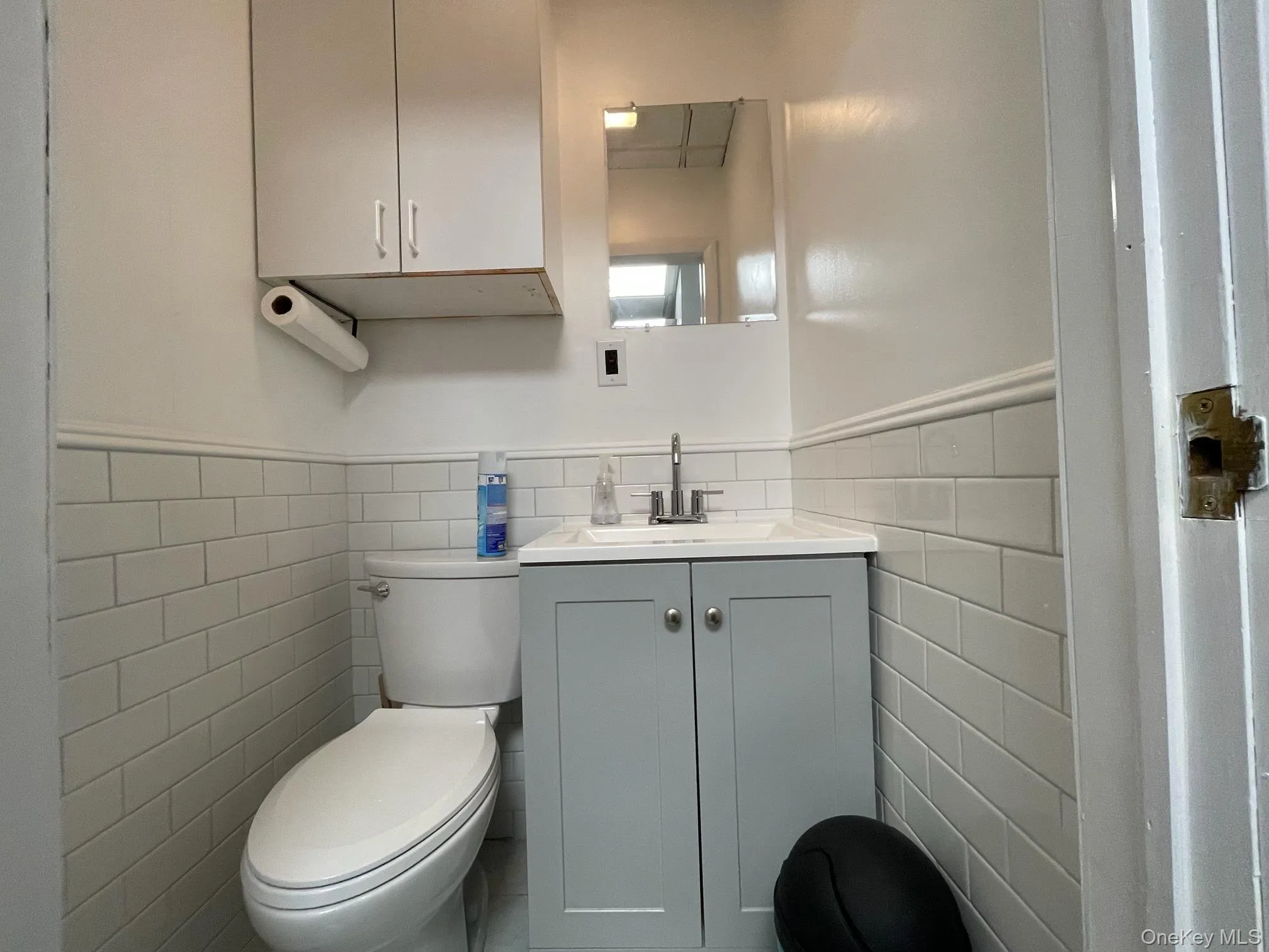 Half bathroom with vanity, wainscoting, and tile walls Half bathroom with vanity, wainscoting, and tile walls