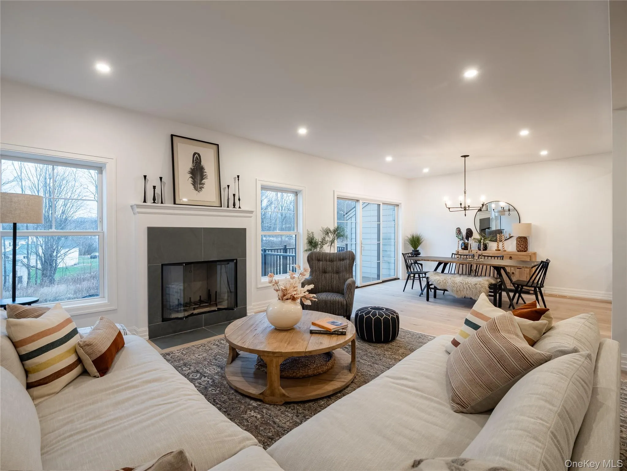 Living room featuring recessed lighting, wood finished floors, a tile fireplace, and a chandelier Living room featuring recessed lighting, wood finished floors, a tile fireplace, and a chandelier