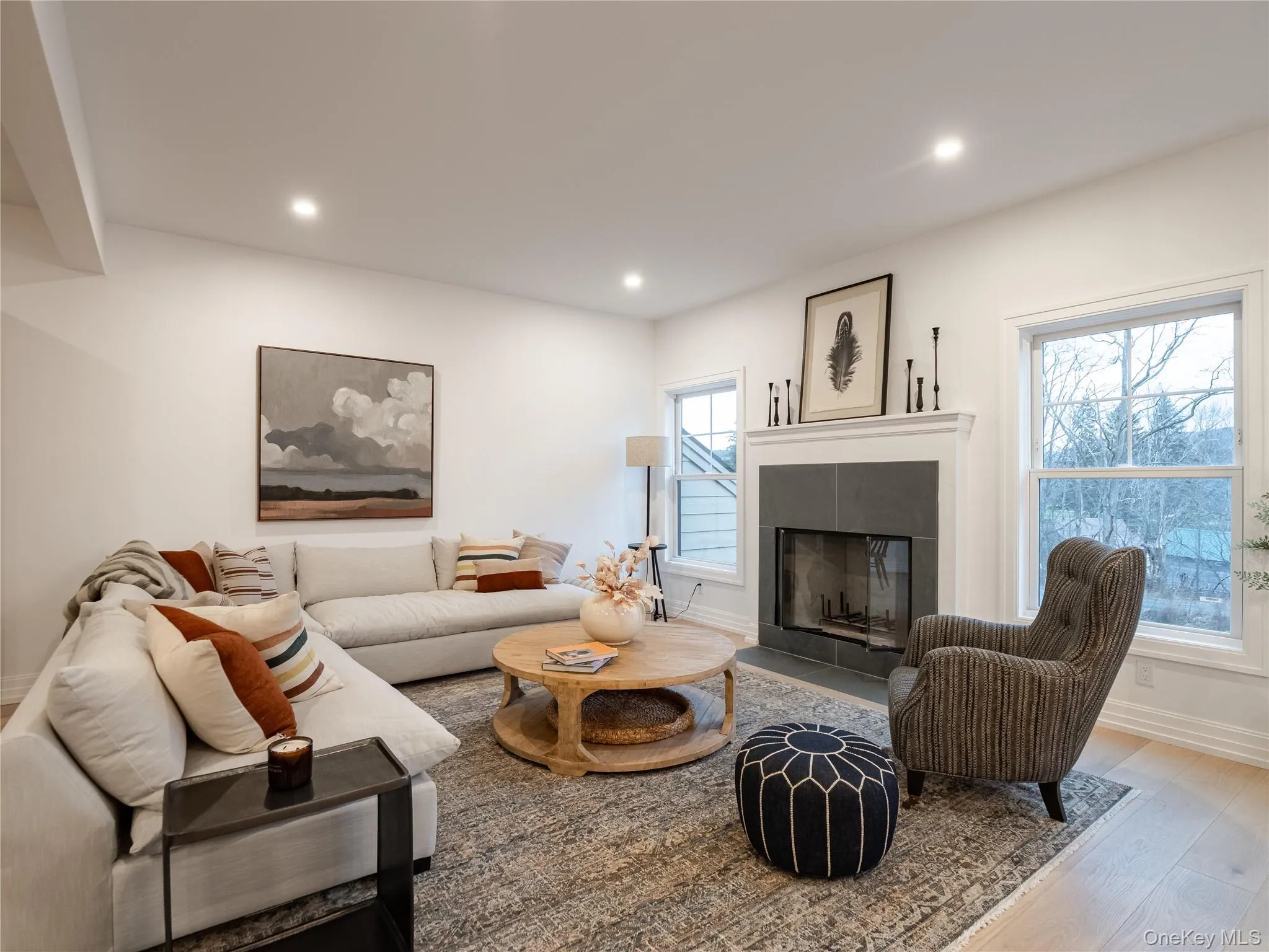 Living area featuring wood finished floors, a tiled fireplace, and recessed lighting Living area featuring wood finished floors, a tiled fireplace, and recessed lighting
