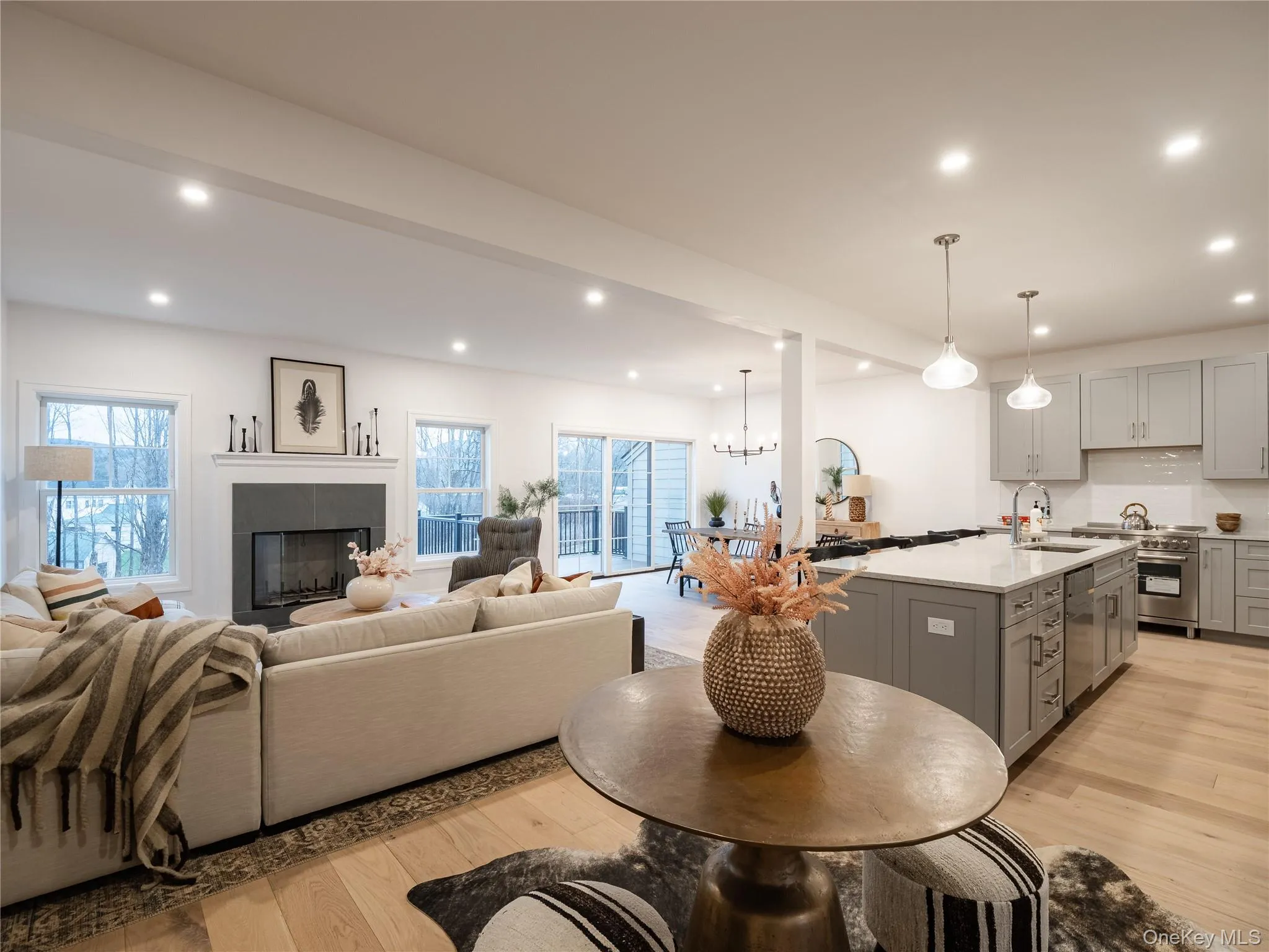 Kitchen featuring gray cabinetry, recessed lighting, light wood finished floors, pendant lighting, and a tiled fireplace Kitchen featuring gray cabinetry, recessed lighting, light wood finished floors, pendant lighting, and a tiled fireplace
