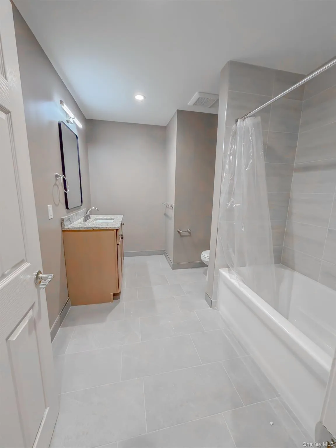 Full bath with shower / bath combo, vanity, and light tile patterned floors Full bath with shower / bath combo, vanity, and light tile patterned floors
