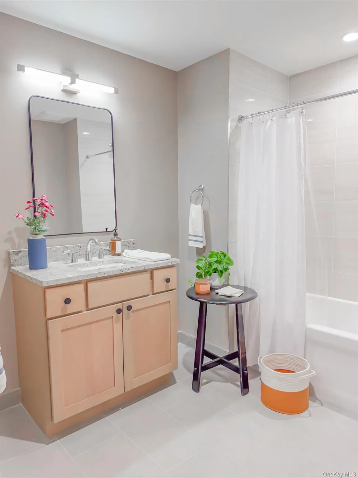 Bathroom with vanity, shower / bath combo, and light tile patterned floors Bathroom with vanity, shower / bath combo, and light tile patterned floors