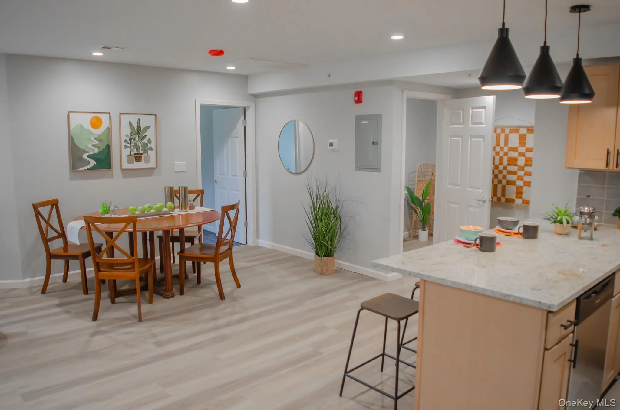 Kitchen featuring light stone countertops, a breakfast bar, pendant lighting, electric panel, and stainless steel dishwasher Kitchen featuring light stone countertops, a breakfast bar, pendant lighting, electric panel, and stainless steel dishwasher