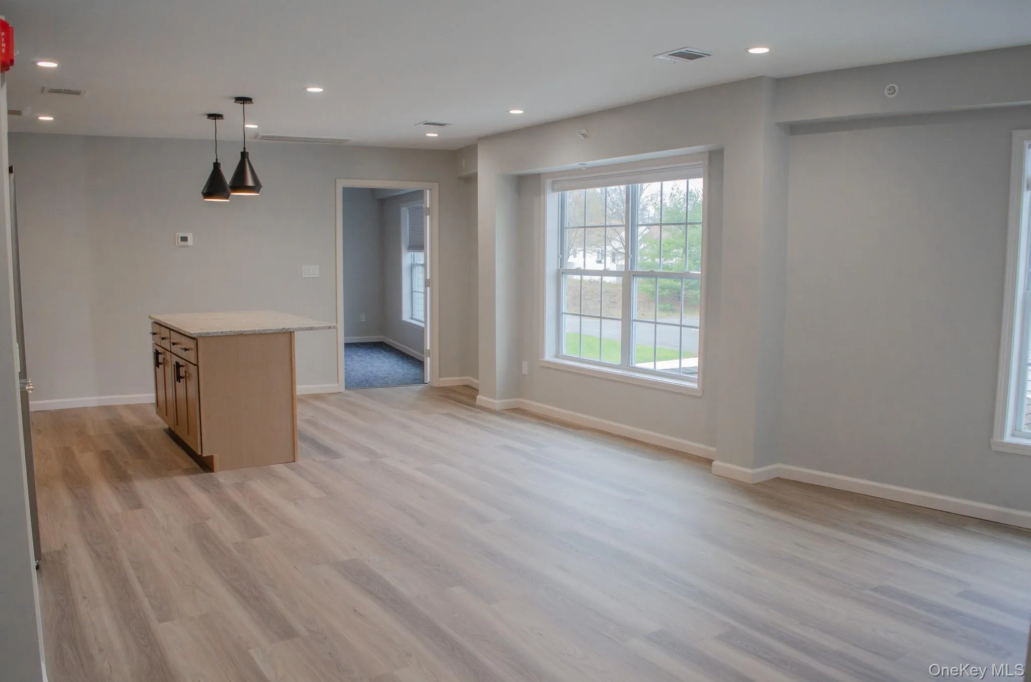 Kitchen with hanging light fixtures, recessed lighting, light wood-style flooring, light stone counters, and a center island Kitchen with hanging light fixtures, recessed lighting, light wood-style flooring, light stone counters, and a center island