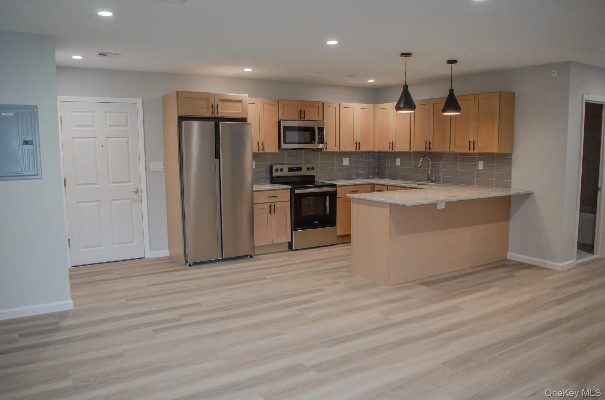 Kitchen with appliances with stainless steel finishes, light brown cabinets, decorative light fixtures, and recessed lighting Kitchen with appliances with stainless steel finishes, light brown cabinets, decorative light fixtures, and recessed lighting