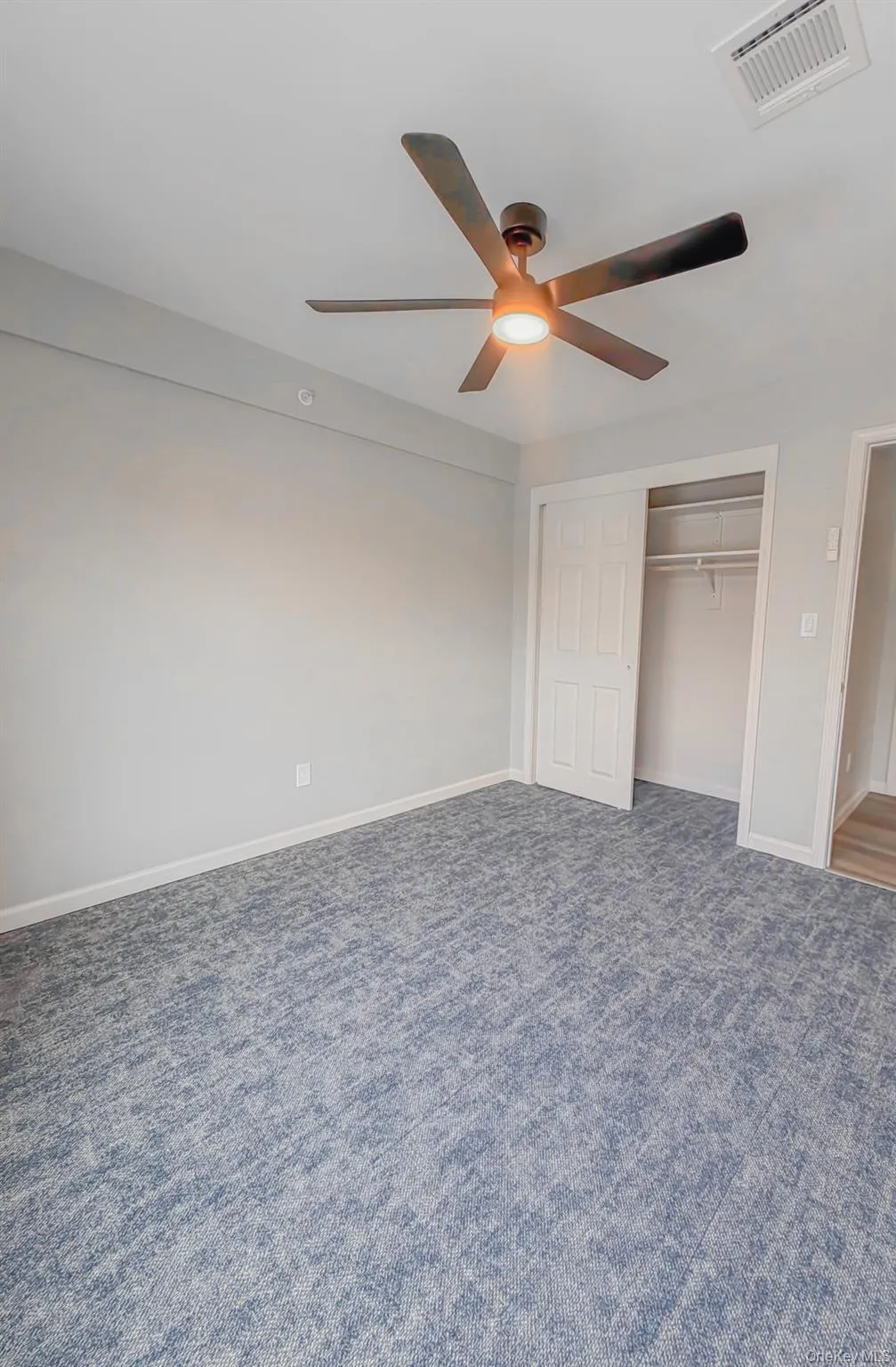 Unfurnished bedroom featuring ceiling fan, a closet, and dark colored carpet Unfurnished bedroom featuring ceiling fan, a closet, and dark colored carpet