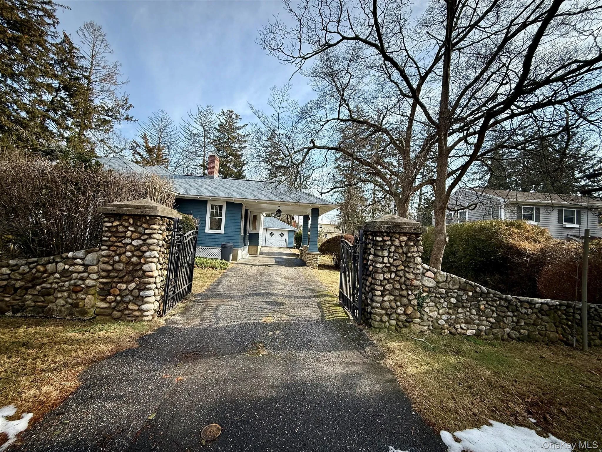 View of front facade featuring a chimney, driveway, and a carport View of front facade featuring a chimney, driveway, and a carport
