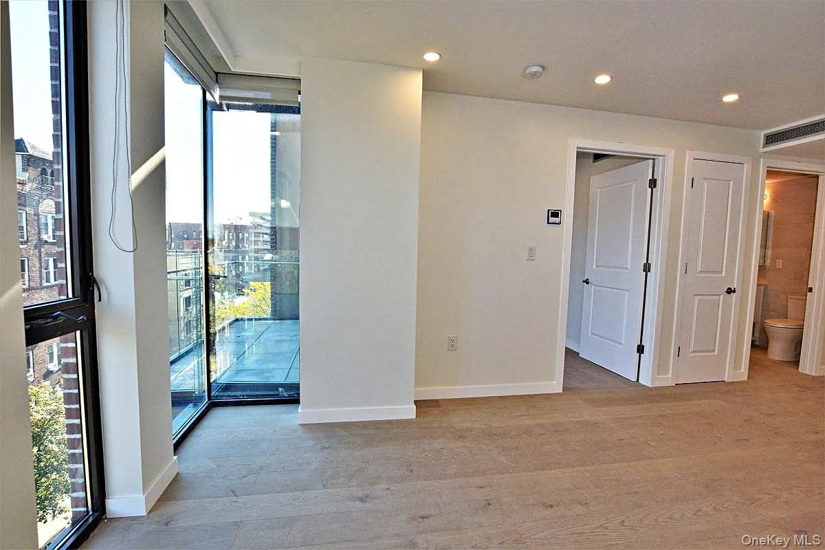 Unfurnished room with healthy amount of natural light, light wood-style flooring, recessed lighting, floor to ceiling windows, and a view of city Unfurnished room with healthy amount of natural light, light wood-style flooring, recessed lighting, floor to ceiling windows, and a view of city