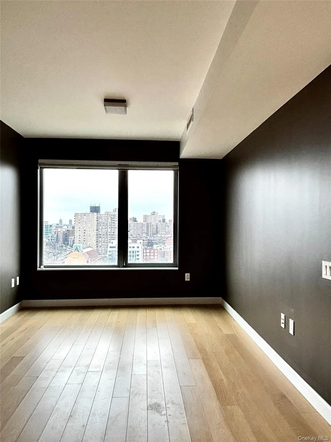 Empty room with light wood-style flooring and a view of city Empty room with light wood-style flooring and a view of city