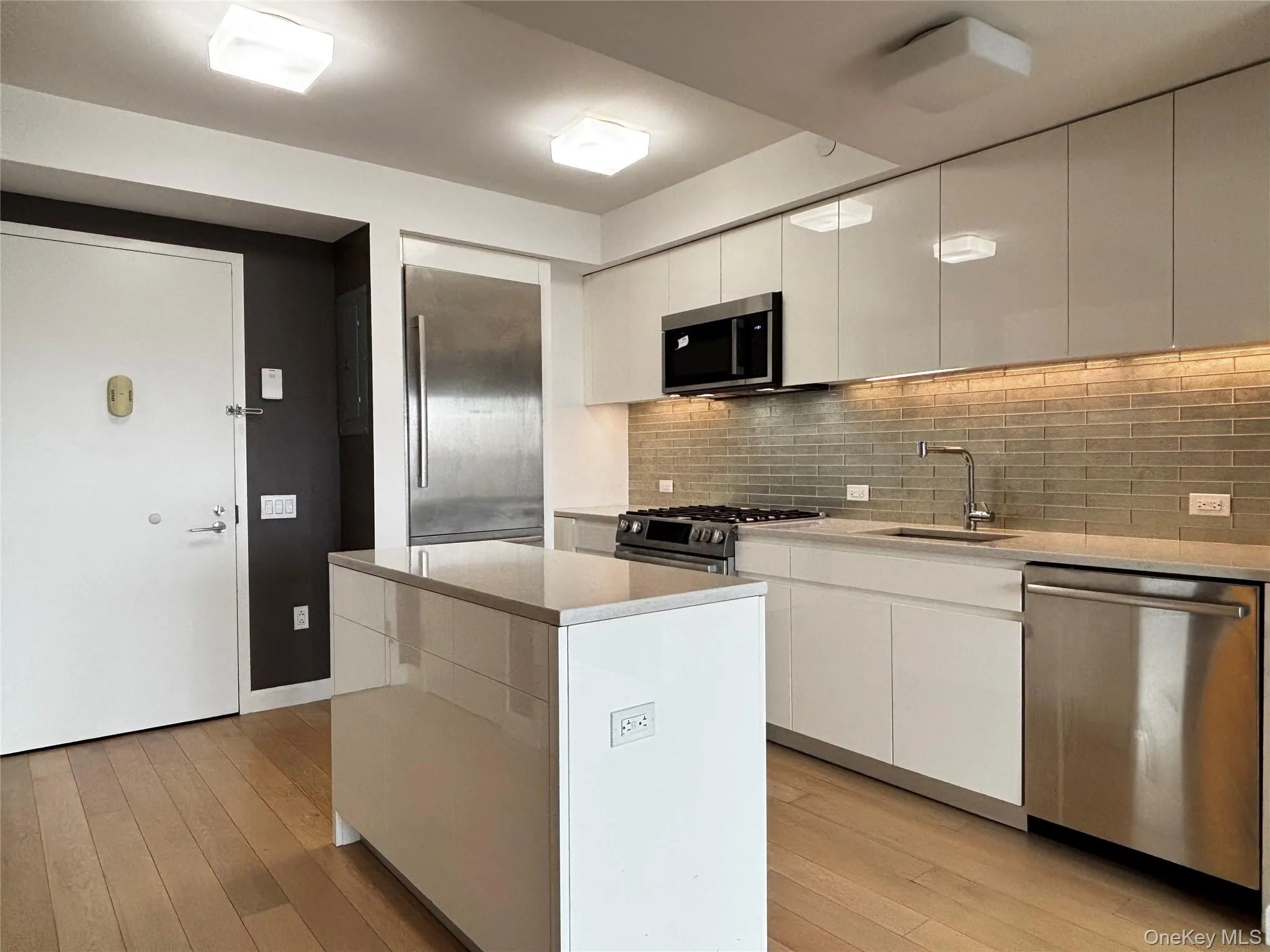 Kitchen with modern cabinets, stainless steel appliances, white cabinets, and a center island Kitchen with modern cabinets, stainless steel appliances, white cabinets, and a center island