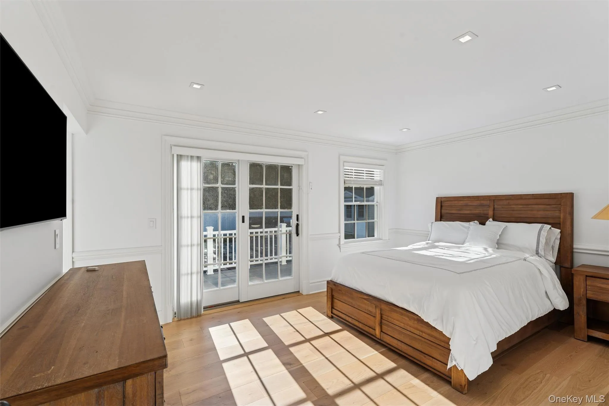 Bedroom featuring access to exterior, crown molding, light wood floors, and recessed lighting. Bedroom featuring access to exterior, crown molding, light wood floors, and recessed lighting.