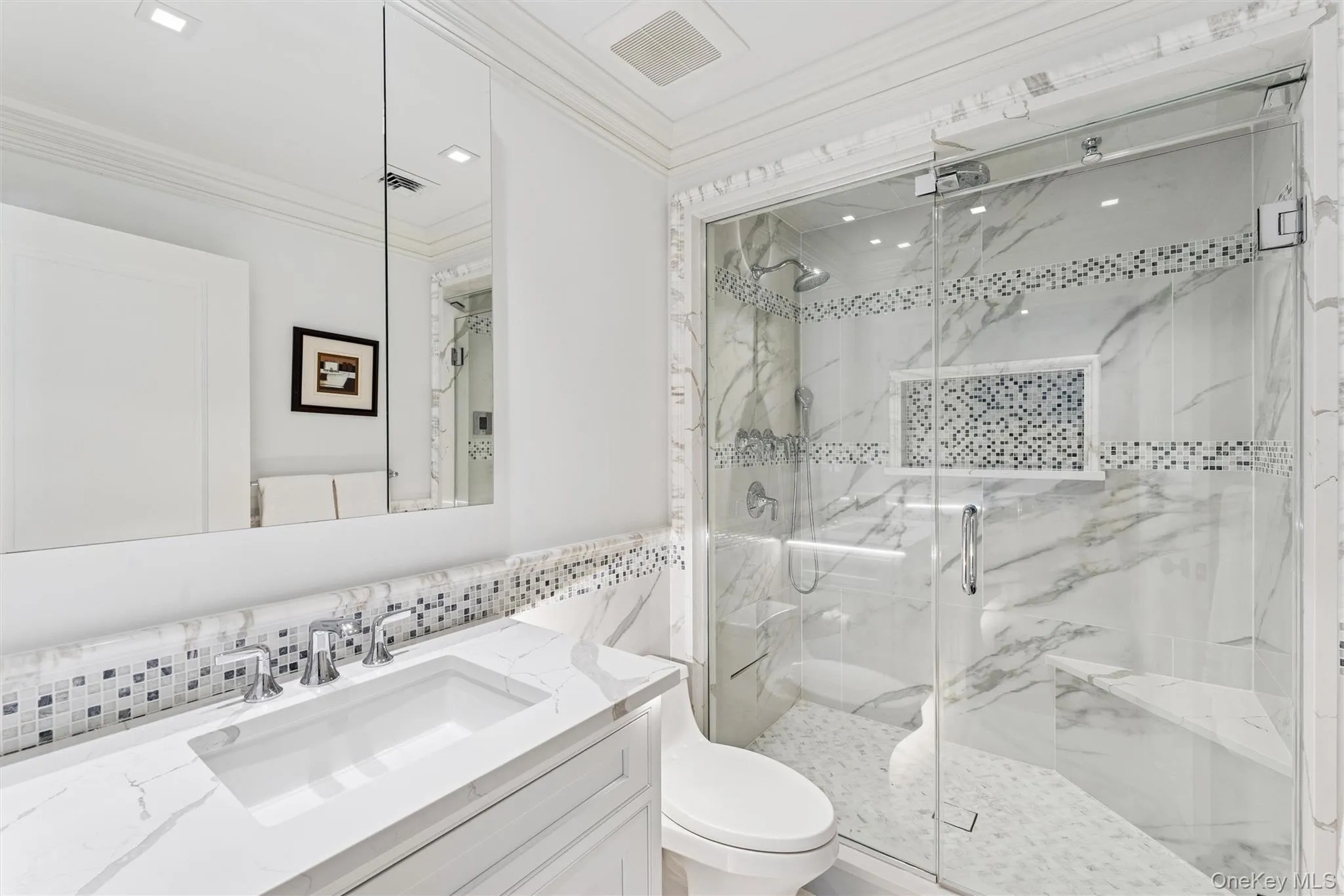 Bathroom inside primary bedroom with crown molding, custom vanity, marble finish shower, tile walls, and a stunning backsplash. Bathroom inside primary bedroom with crown molding, custom vanity, marble finish shower, tile walls, and a stunning backsplash.